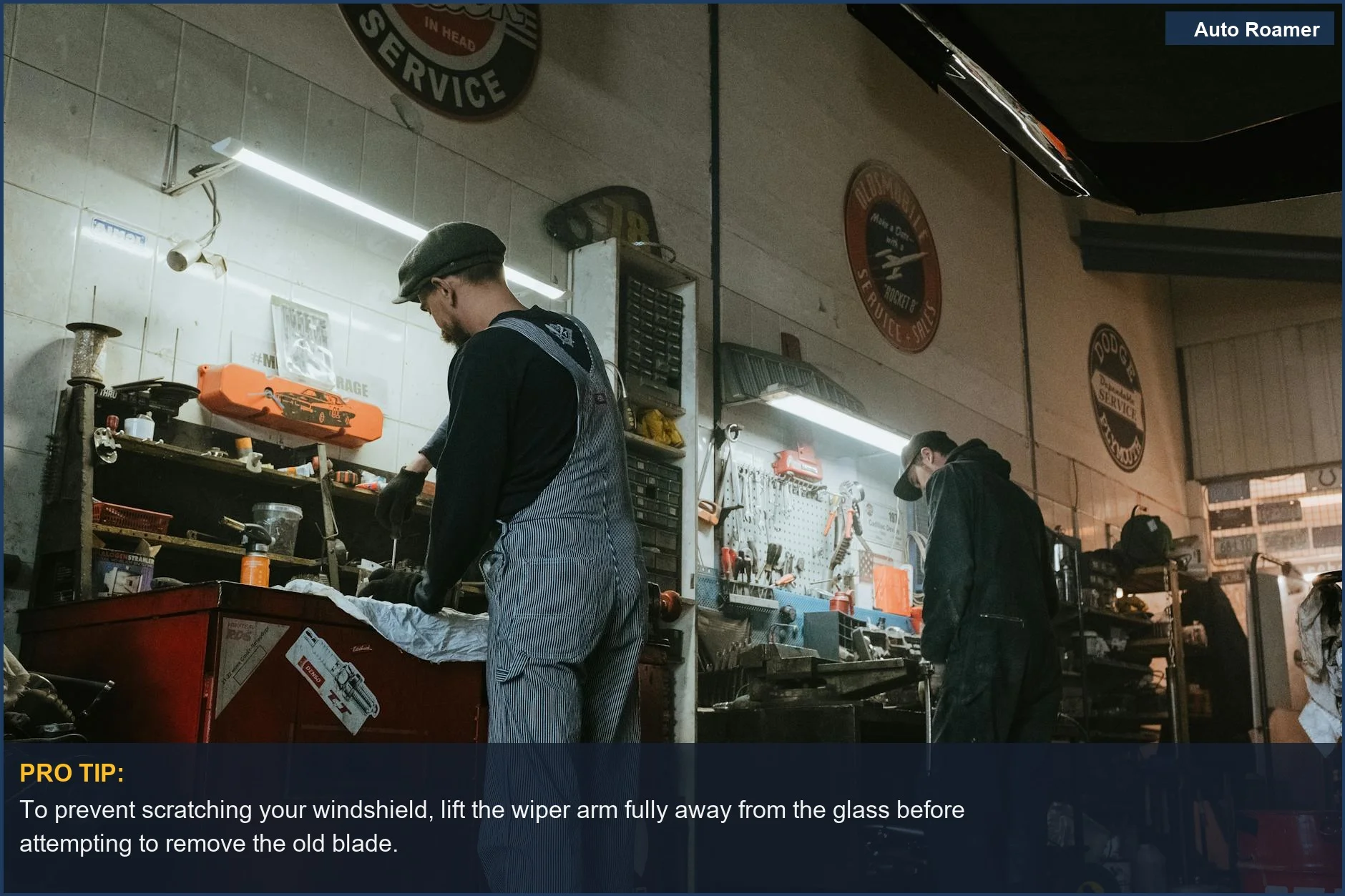 Two mechanics collaborating in a garage, one holding a new wiper blade ready for installation.