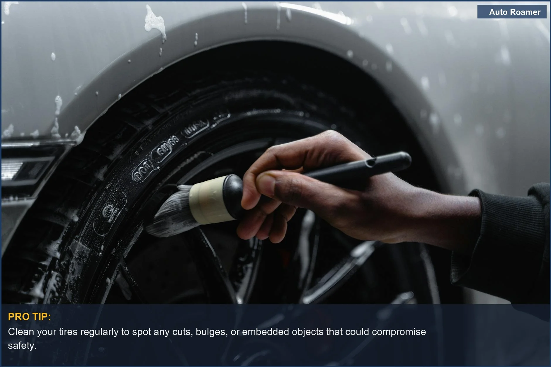 Hand cleaning car tire with a brush, demonstrating a basic maintenance step for tires.
