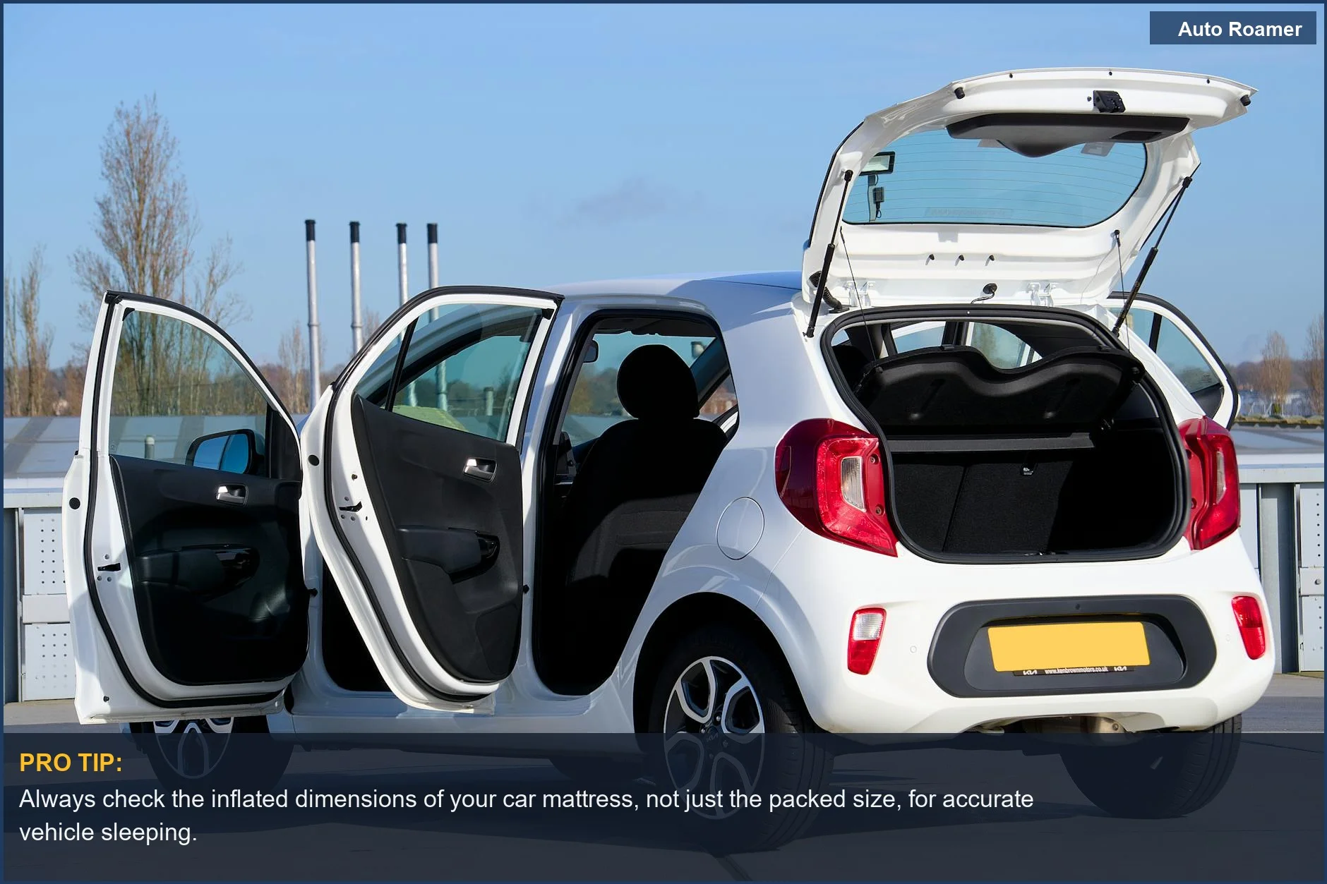White compact car with open doors and trunk, showcasing vehicle sleeping potential on an urban street.