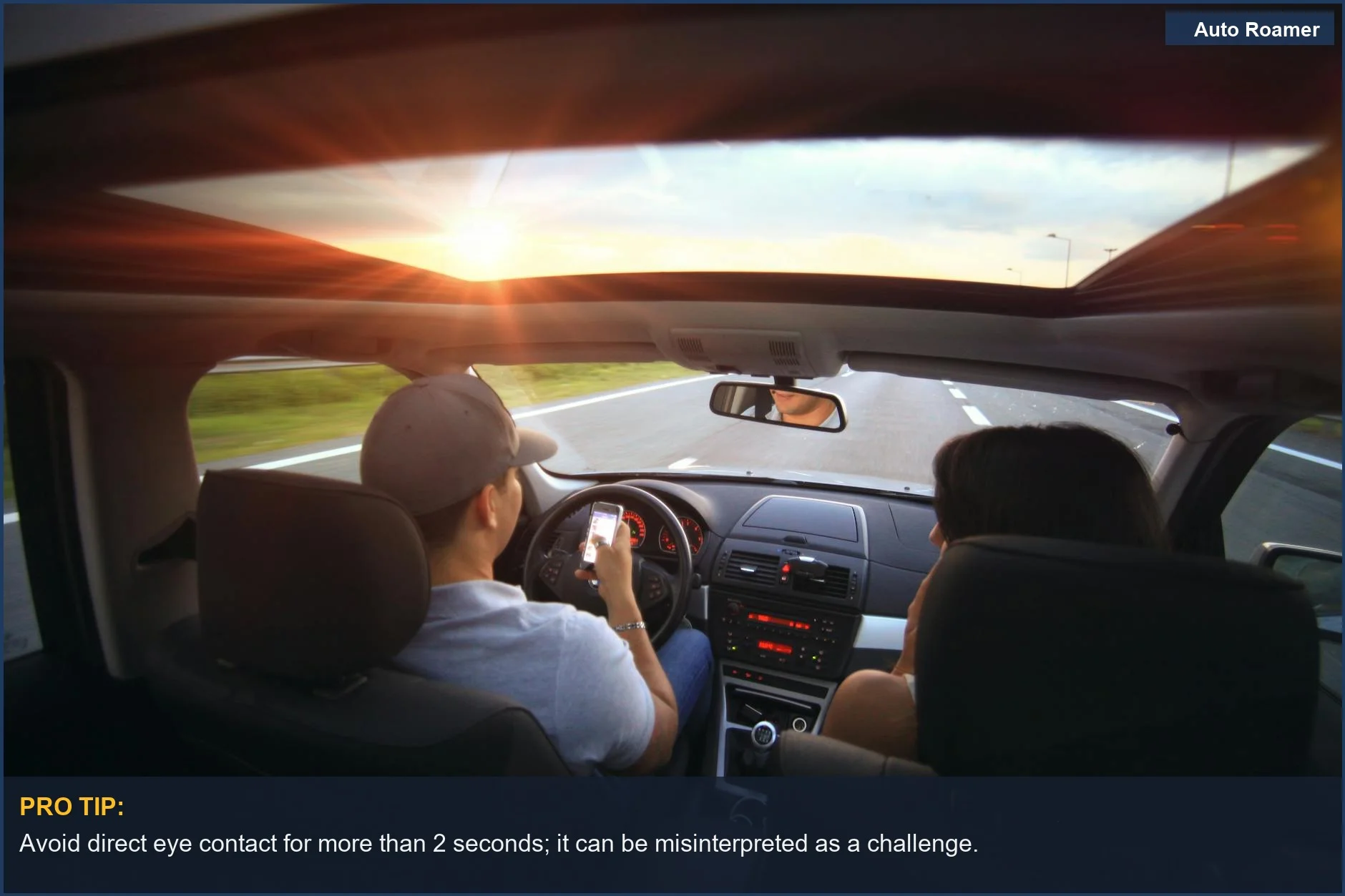 Driver using phone at sunset, a safety risk for road rage de-escalation.