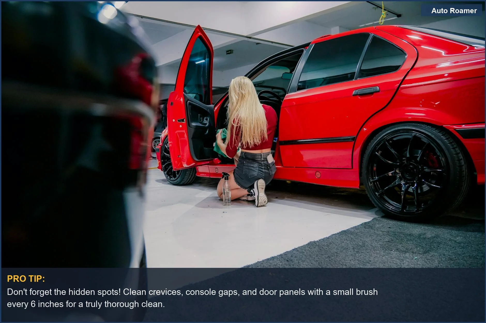A dedicated woman kneels, meticulously deep cleaning a car interior before a road trip in a red BMW, ensuring every spot is spotless.