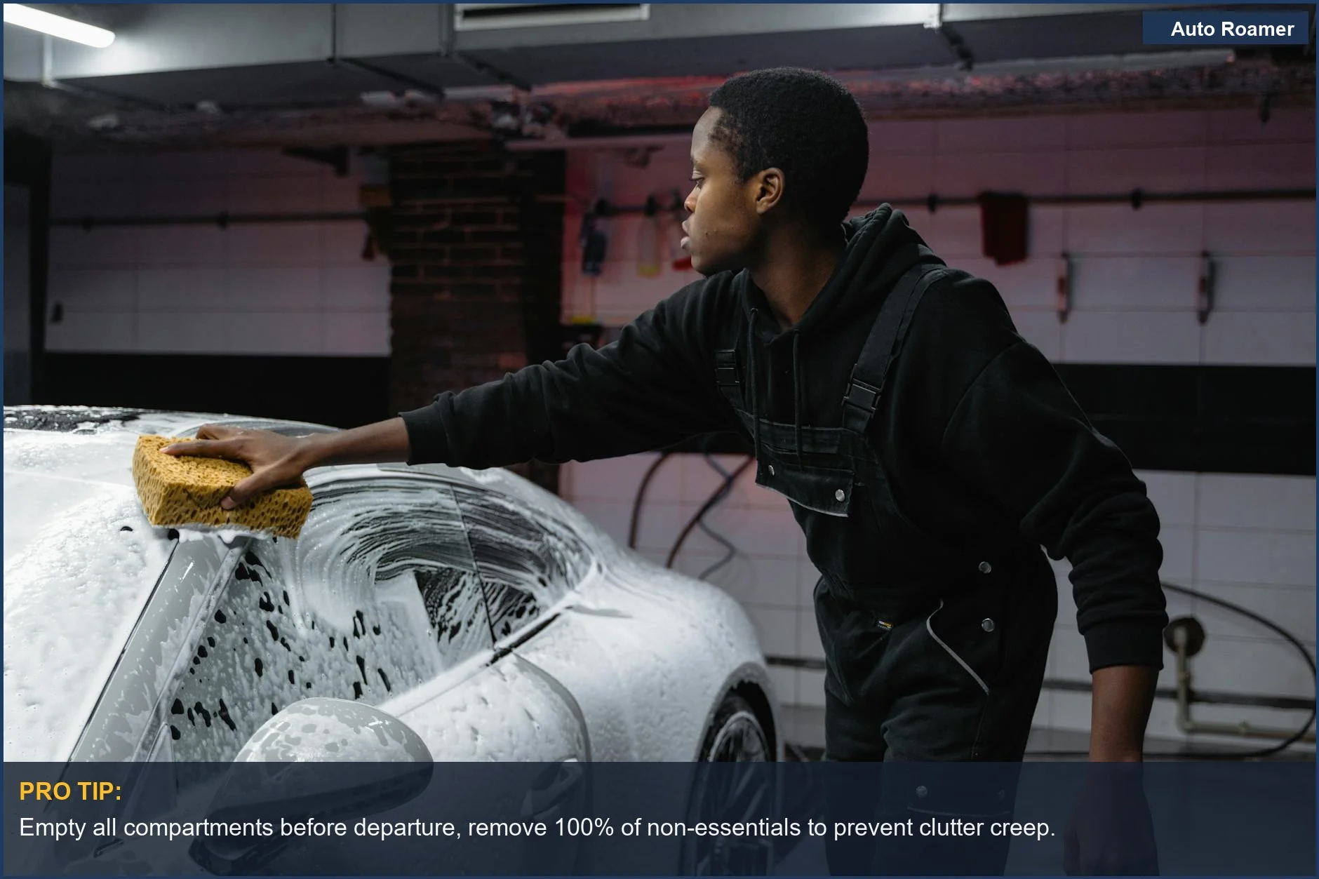 A person deep cleaning a car with a sponge in a garage, crucial for keeping your vehicle clean during road trips.