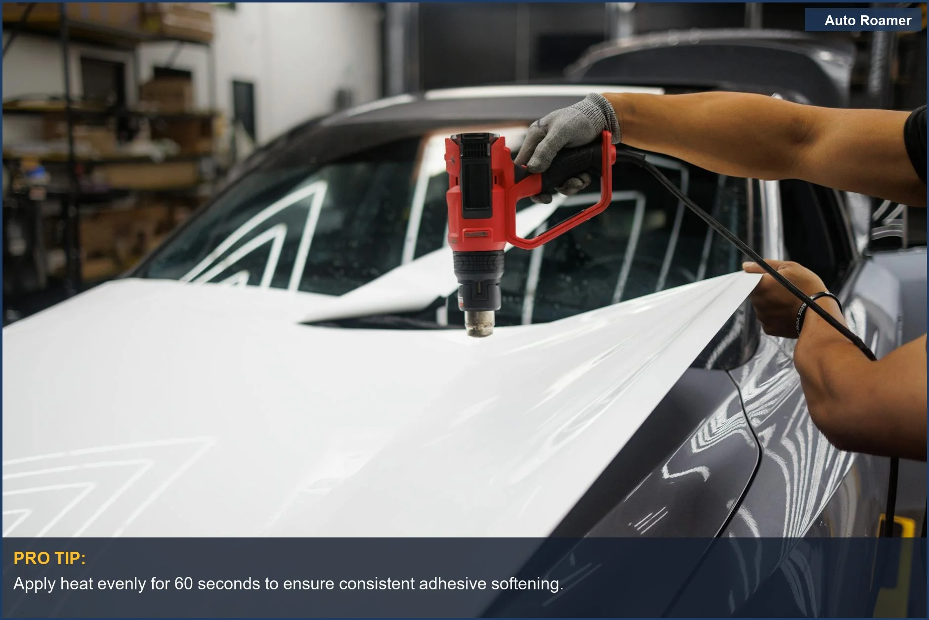Worker using a heat gun to soften adhesive for car sticker removal without damaging paint.