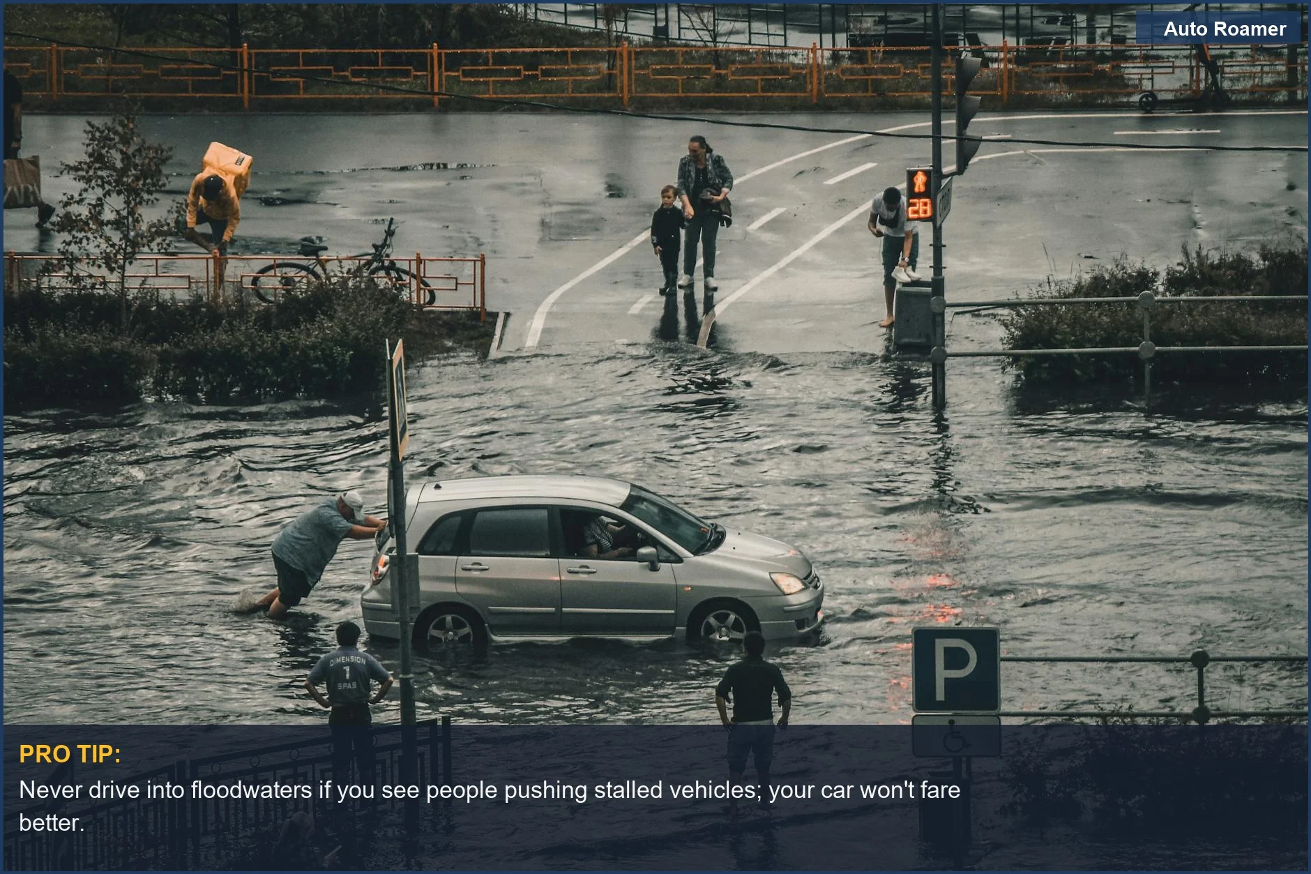 Depicts a flooded city street where people push a stalled car, highlighting challenges of navigating flooded roads safely.