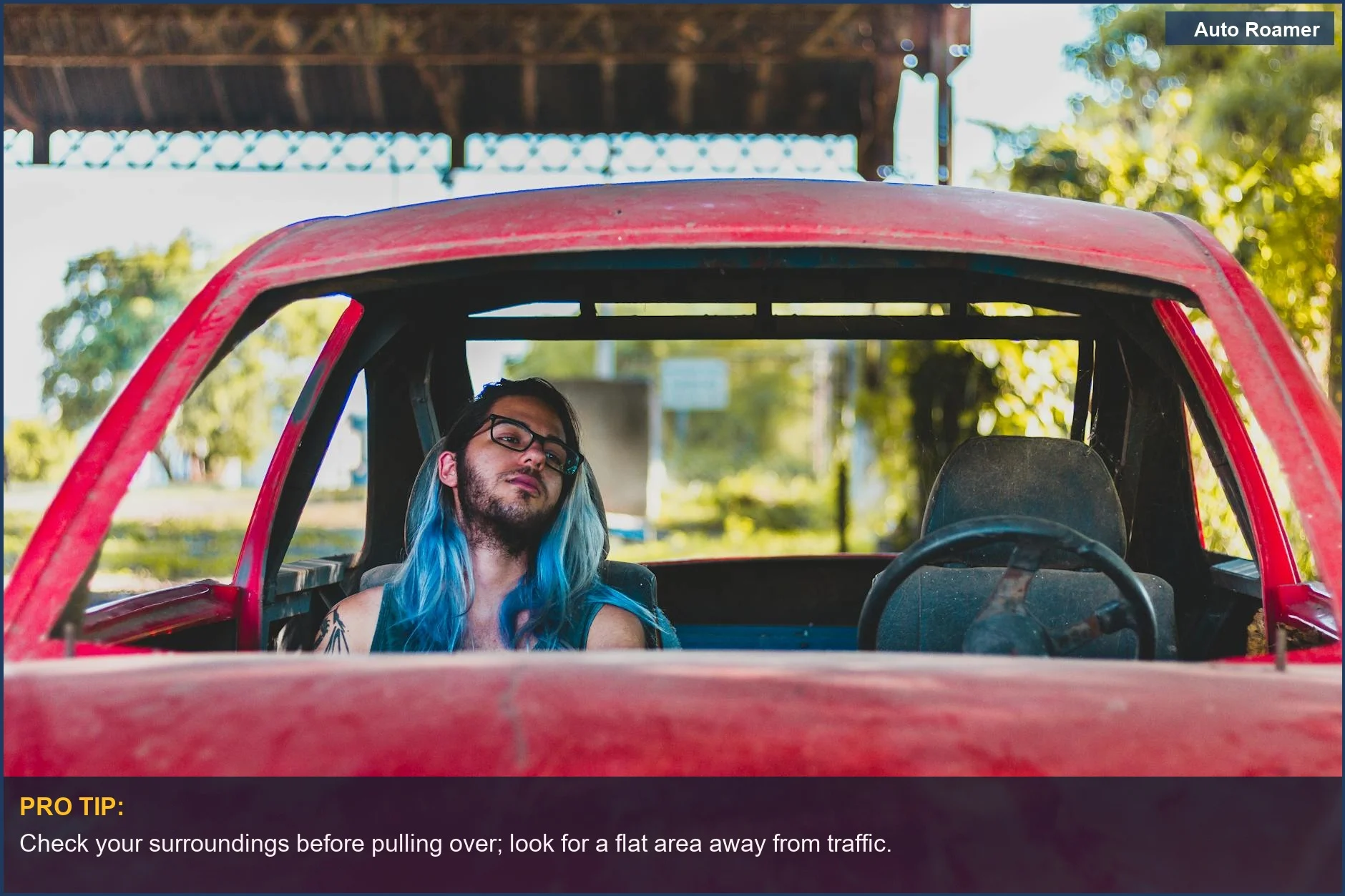 Person resting in a red abandoned car parked on the highway shoulder.