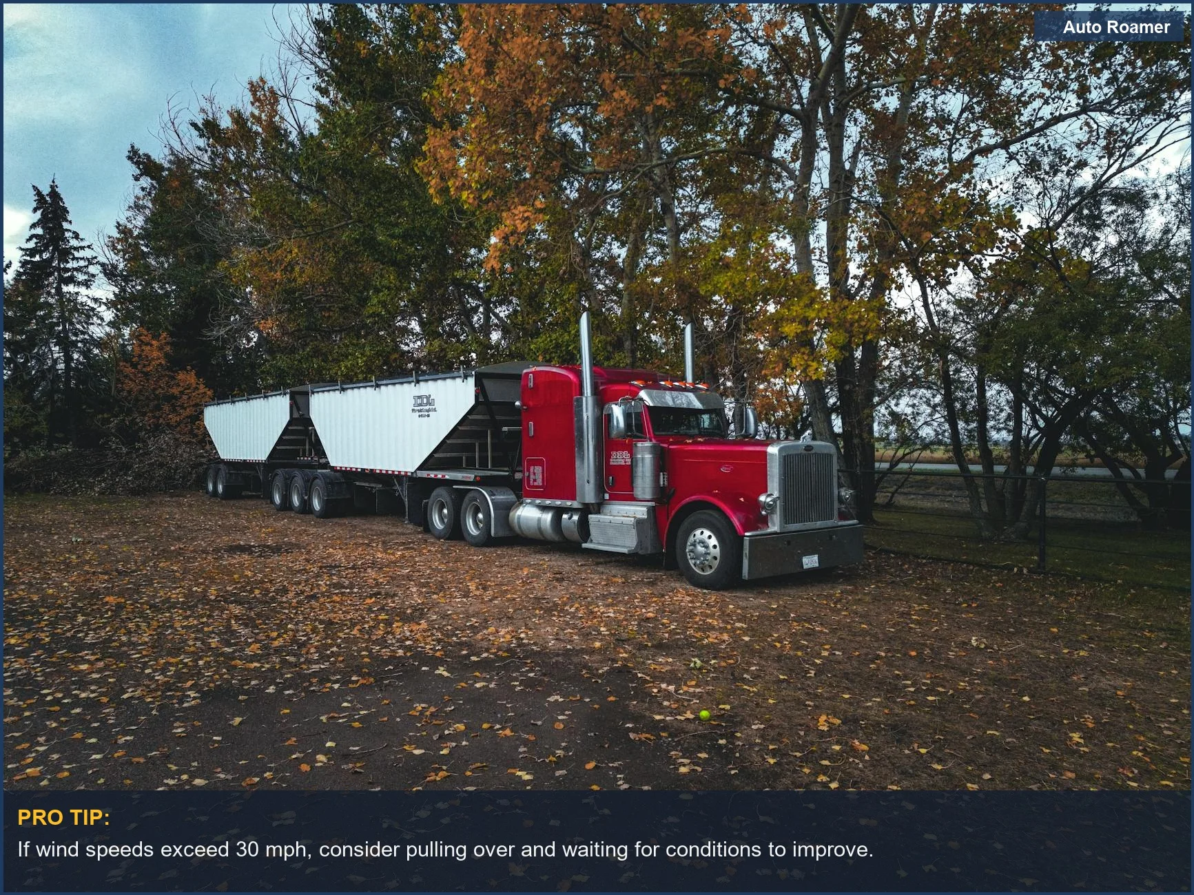 Red trailer truck parked amidst autumn trees in Canada, a visual for wind speed limit for towing.