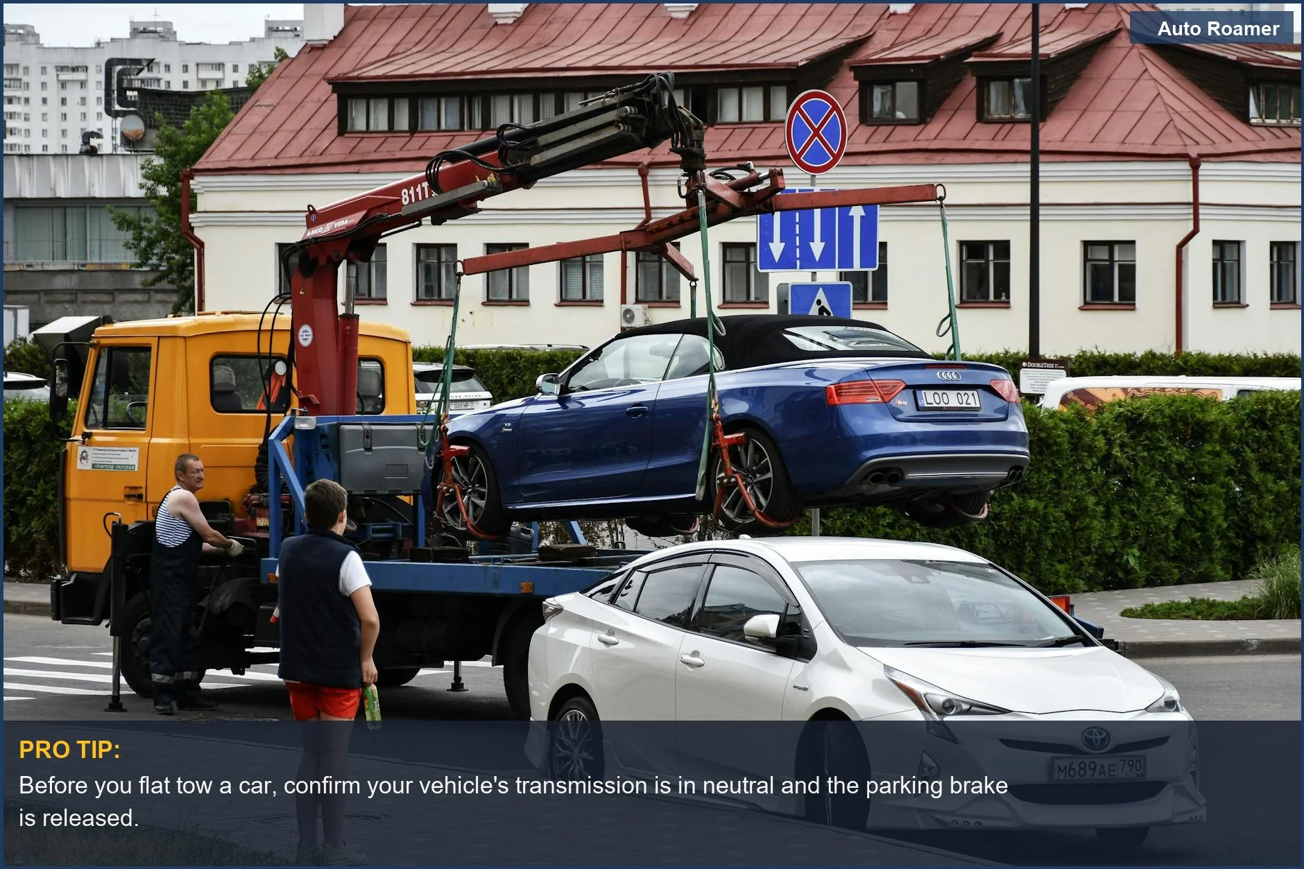 Towing a blue Audi convertible in a bustling city street without a tow truck.