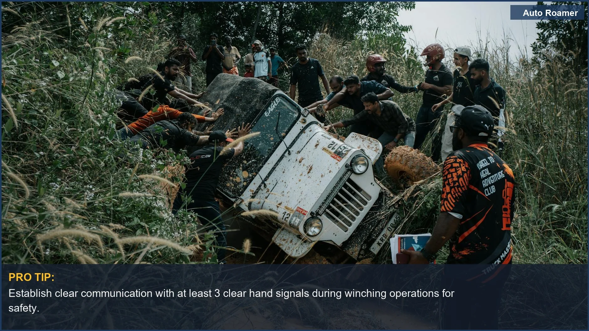 Group of people working together to free a Jeep on an off-road trail, emphasizing winching safety.