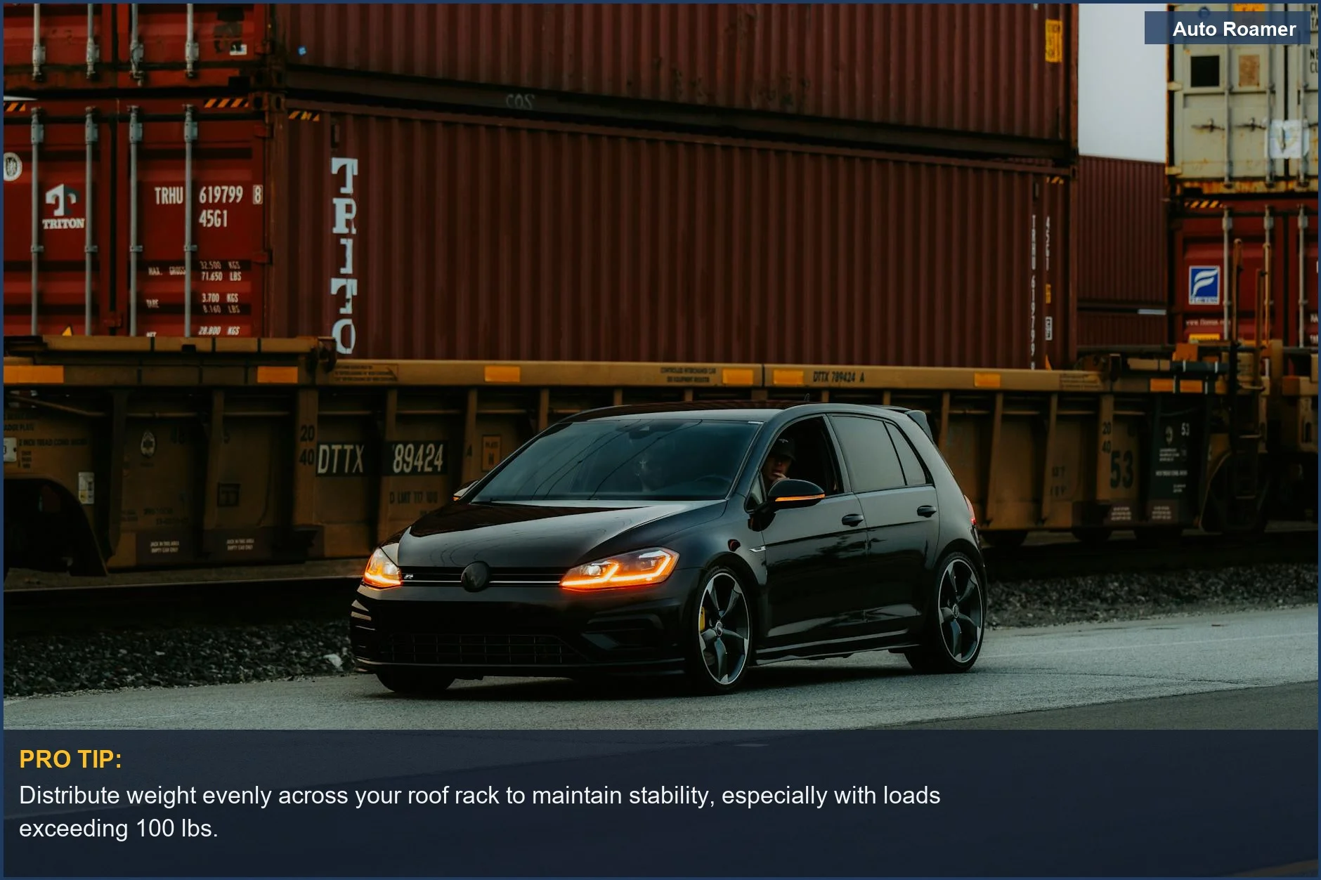 Black car with a loaded roof rack driving past stacked cargo, demonstrating the importance of weight distribution.