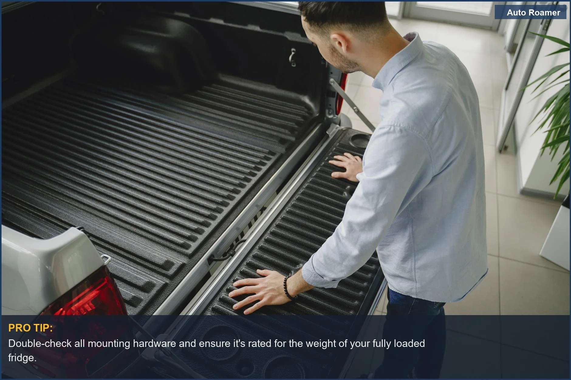 Man inspecting truck tailgate in showroom, considering DIY fridge slide options.