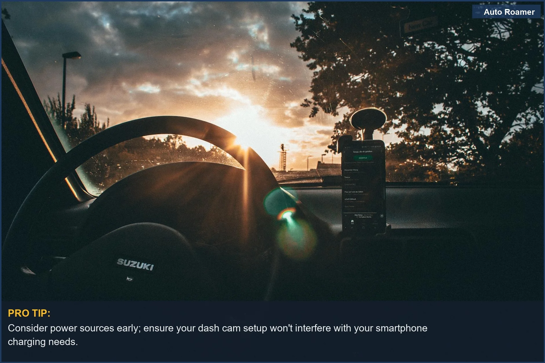 Sunrise viewed through an RV windshield, showcasing the steering wheel and smartphone, ideal for discussing DIY RV dash cam setup.