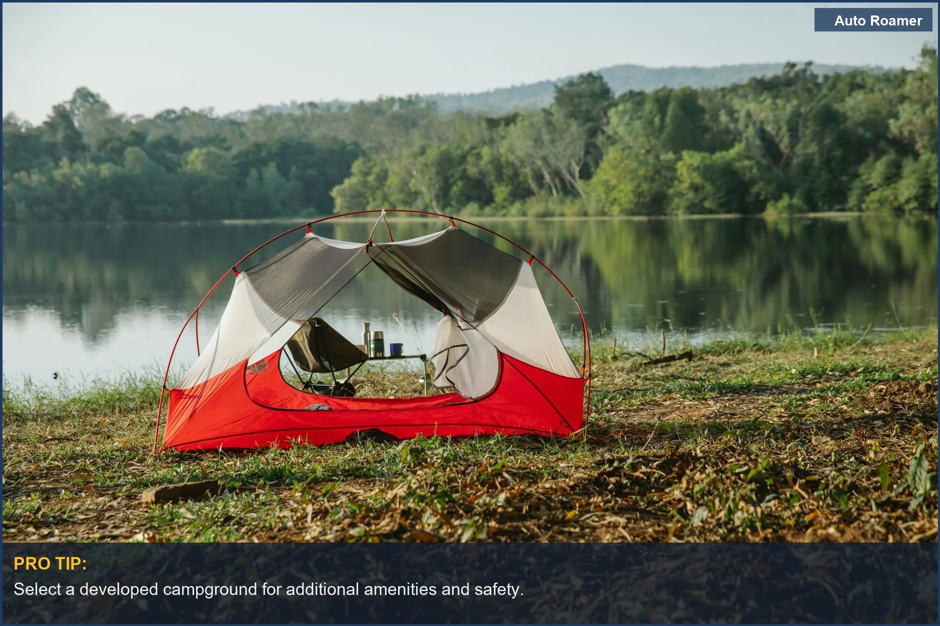 Tent on grass by a lake reflecting trees under a bright sky.