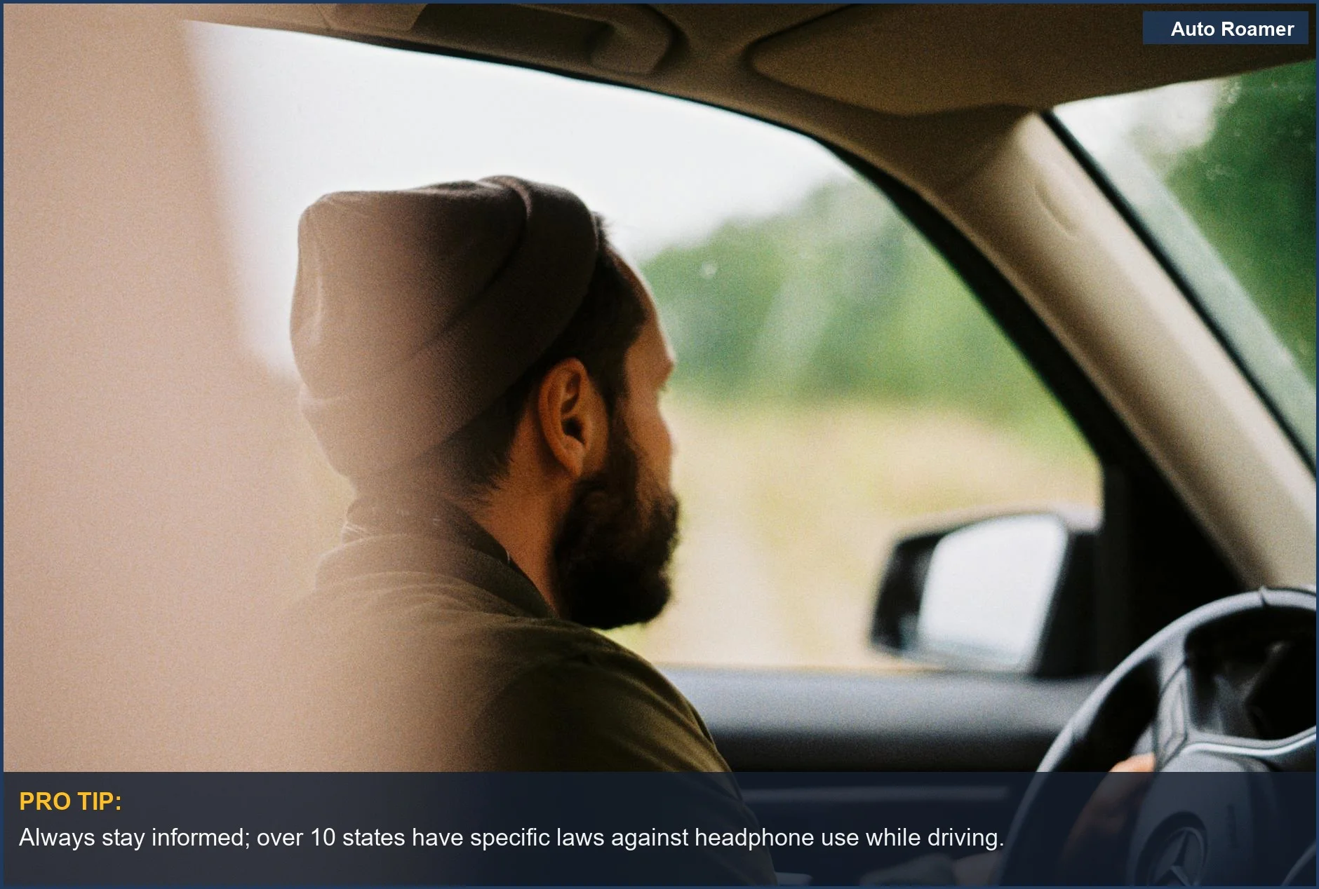 Bearded man wearing a beanie while driving, illustrating the debate on headphone use in cars.