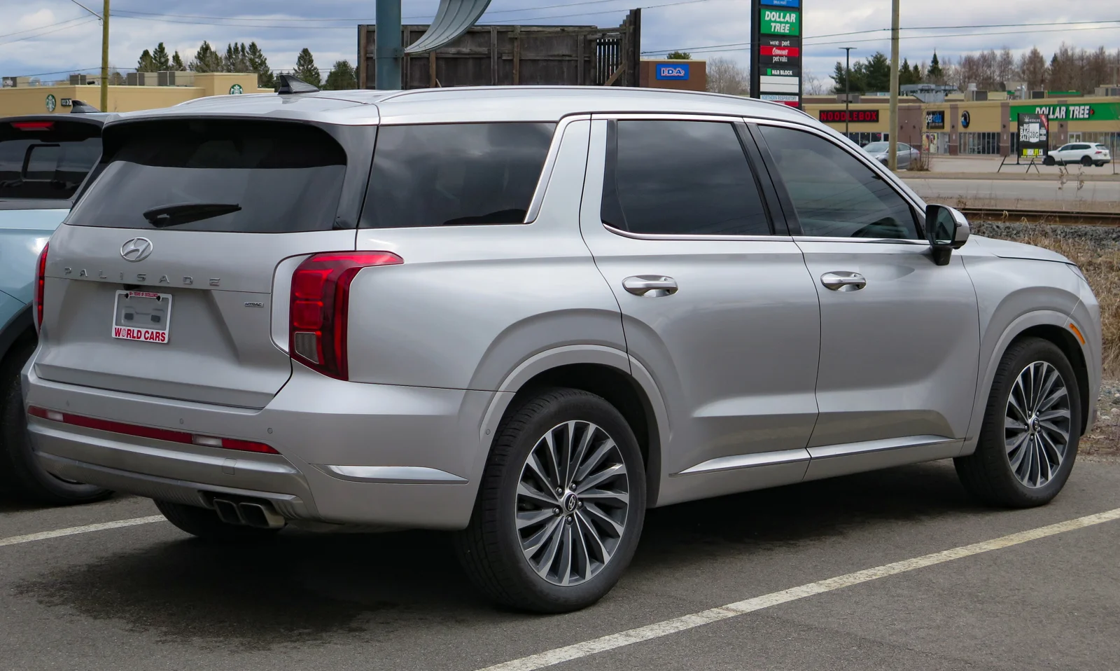Silver Hyundai Palisade, current facelift generation, rear three-quarter view showing the tailgate and rear lights in a parking lot.