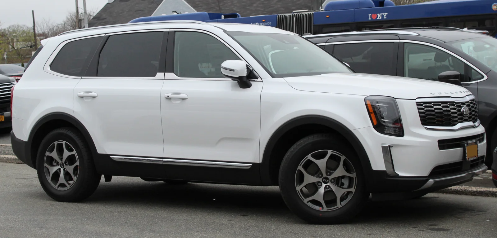 White Kia Telluride, first-generation pre-facelift, side profile view parked at a kerb.