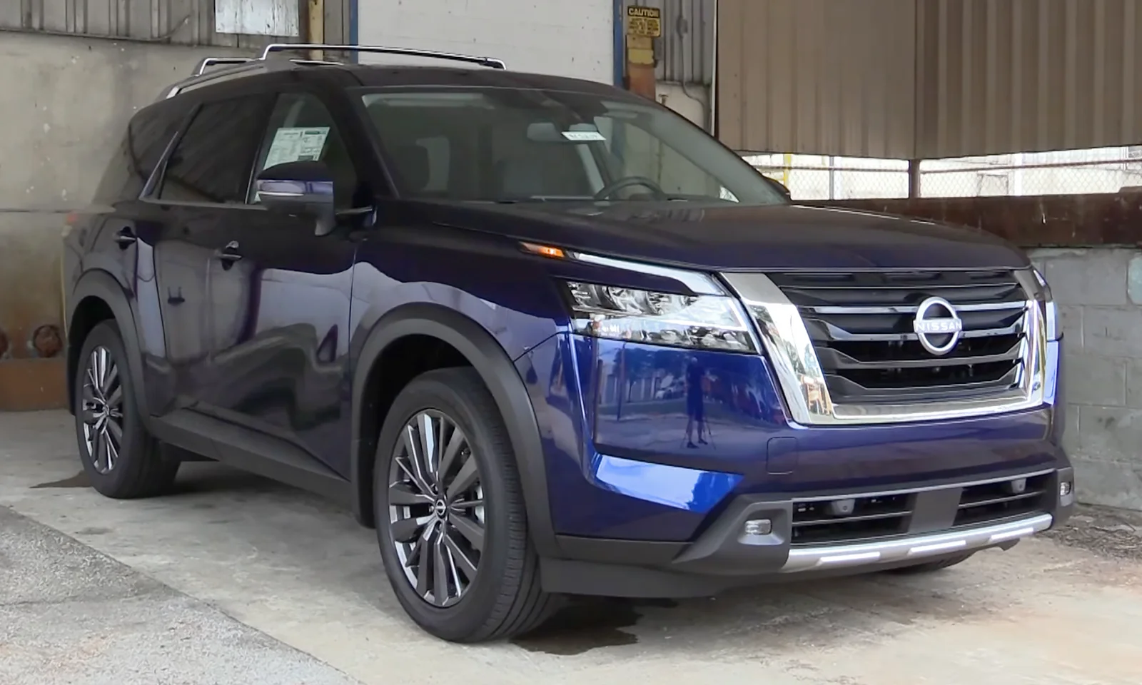 Blue Nissan Pathfinder, current R53 generation, front three-quarter view showing the upright grille and split headlights.