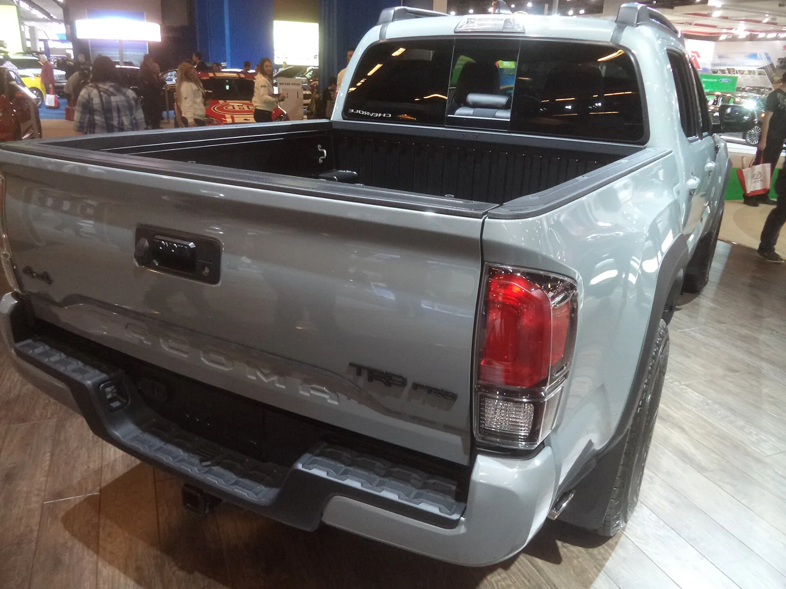 Looking into the open cargo bed of a Toyota Tacoma TRD Pro double cab from the rear three-quarter: the bed floor, the ribbed bed walls, the rail caps along the top of each side, and the closed tailgate that set every camping dimension.