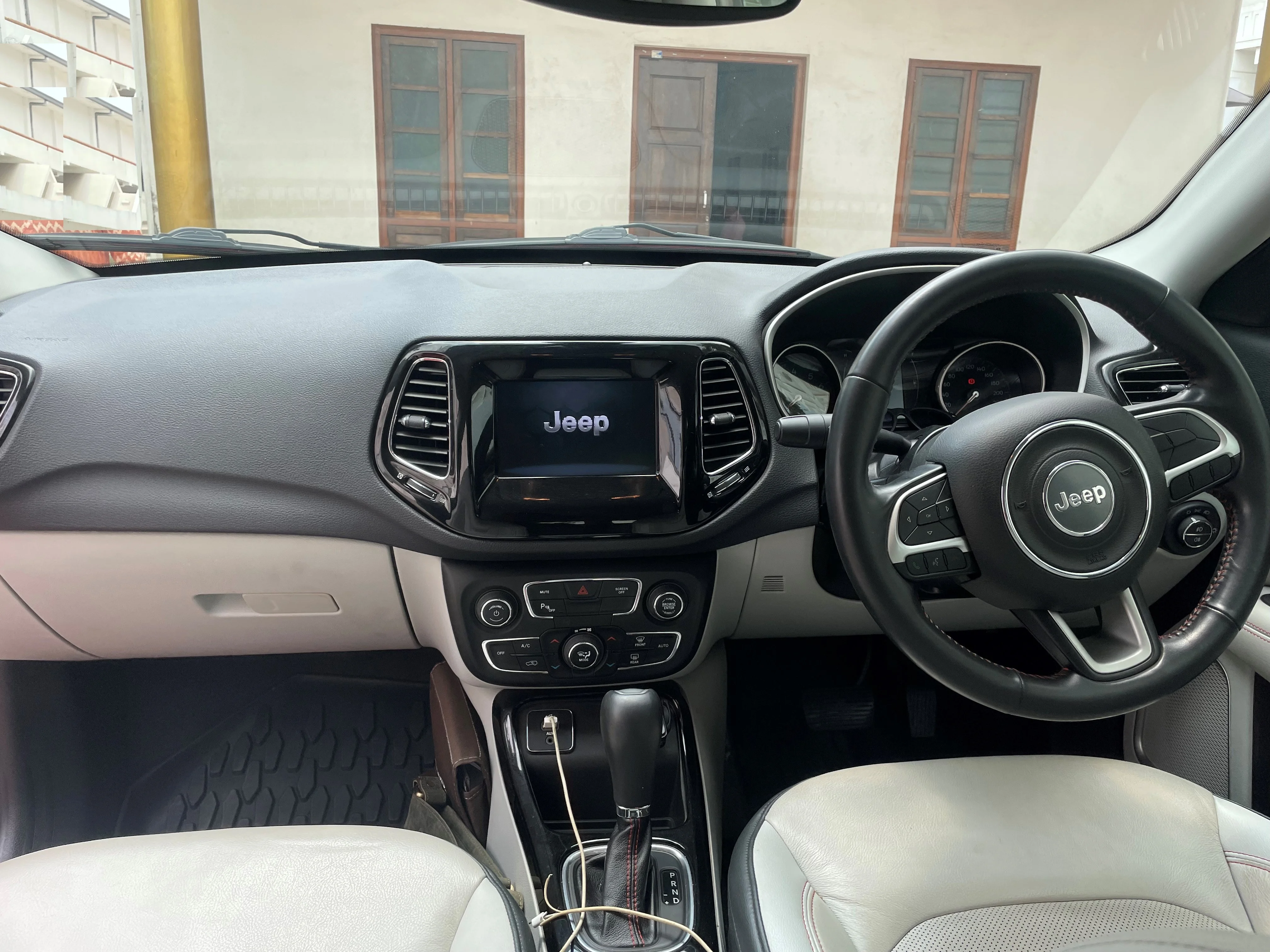 The dashboard and center console of a Jeep Compass (MP generation), showing the cabin storage and power layout a camper works with.