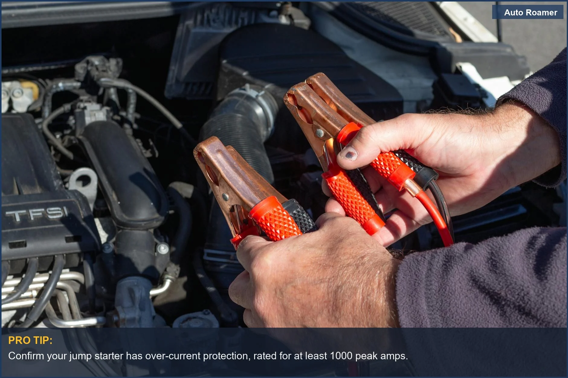 Hands carefully holding jumper cables near a car engine, emphasizing safe jump starter usage.
