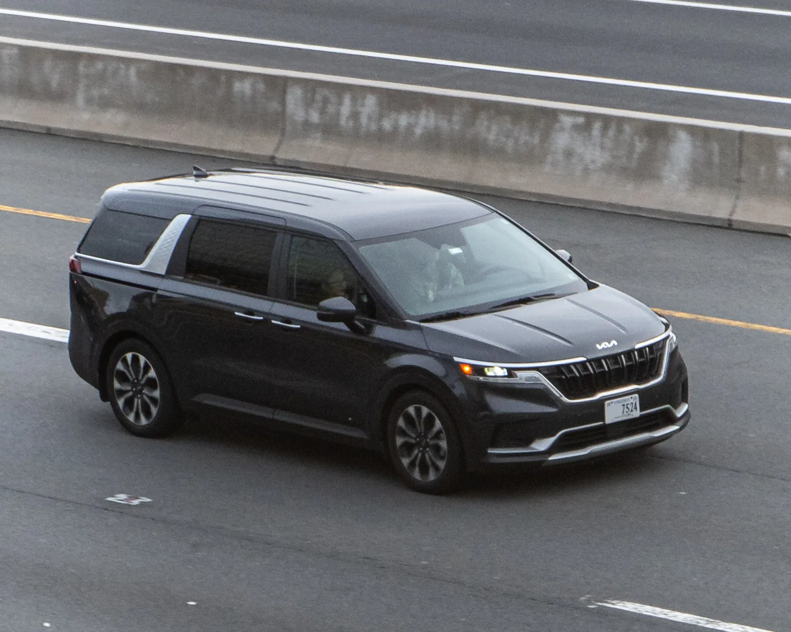 A Kia Carnival minivan on the highway, the van whose cargo dimensions for sleeping this guide measures