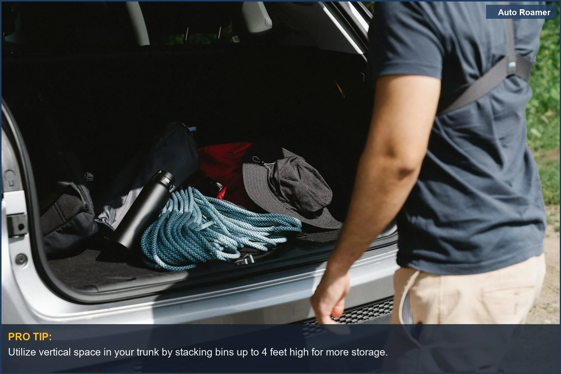 Man organizing camping gear in car trunk to maximize vehicle space.