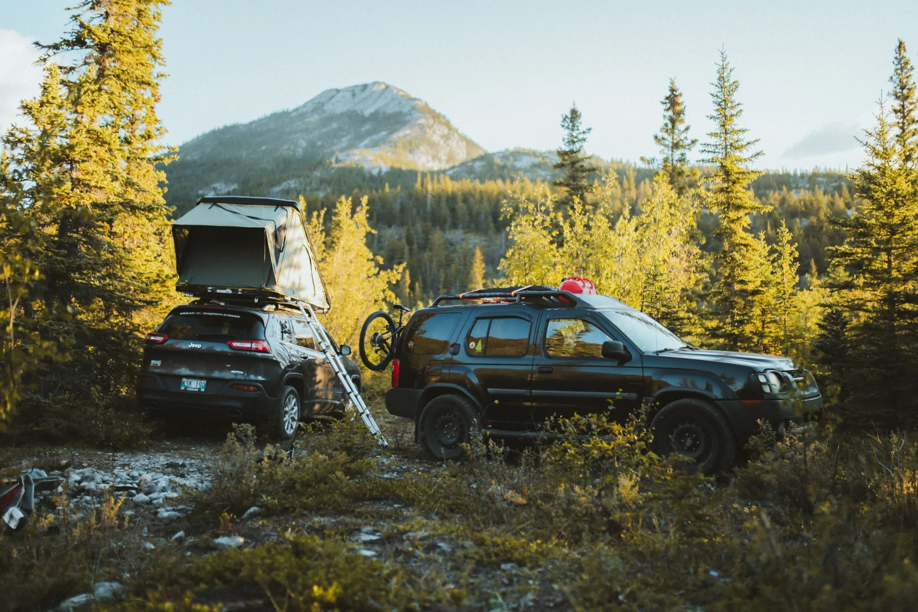 An SUV parked at a remote campsite — the kind of level, quiet ground the CX-50's AWD and ground clearance let you reach to sleep.