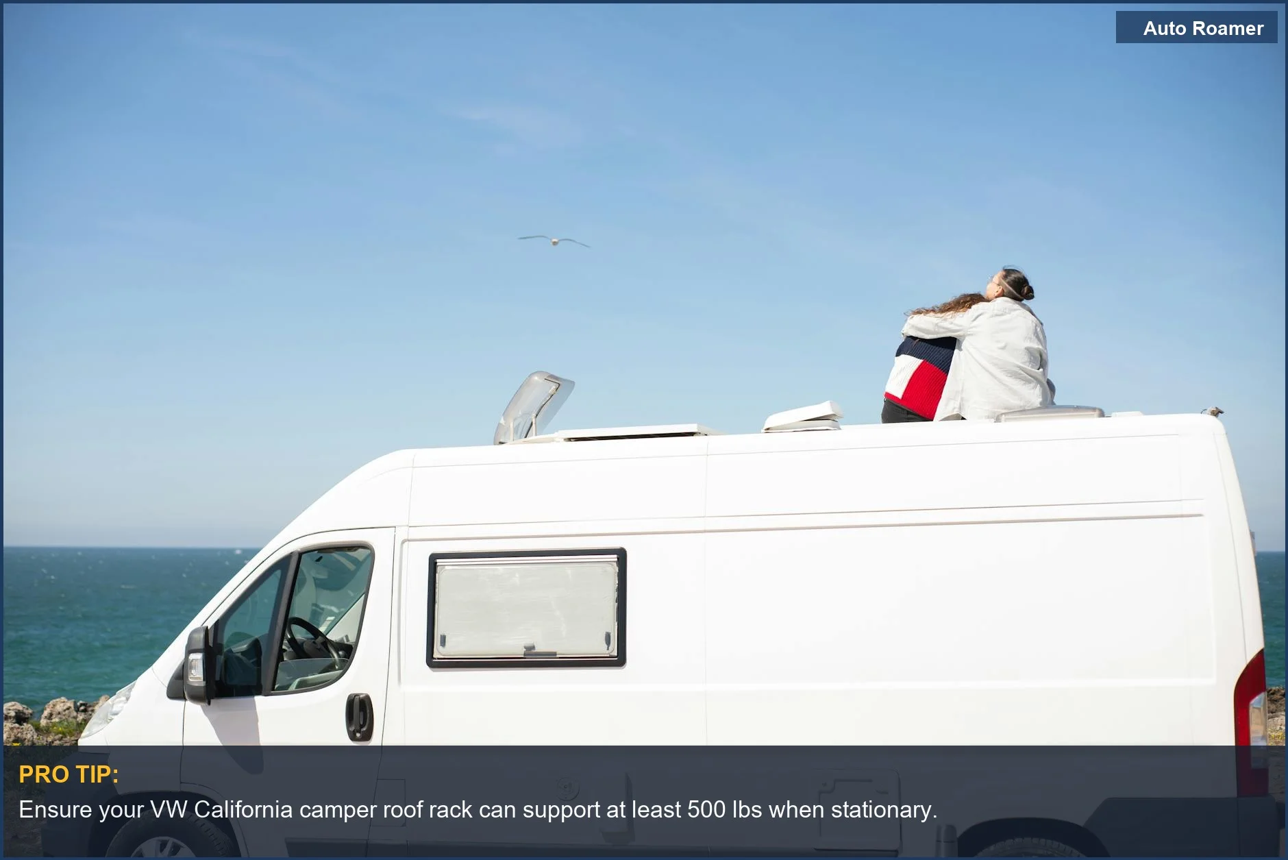 Couple enjoying ocean view from VW California camper van with rooftop tent installed.