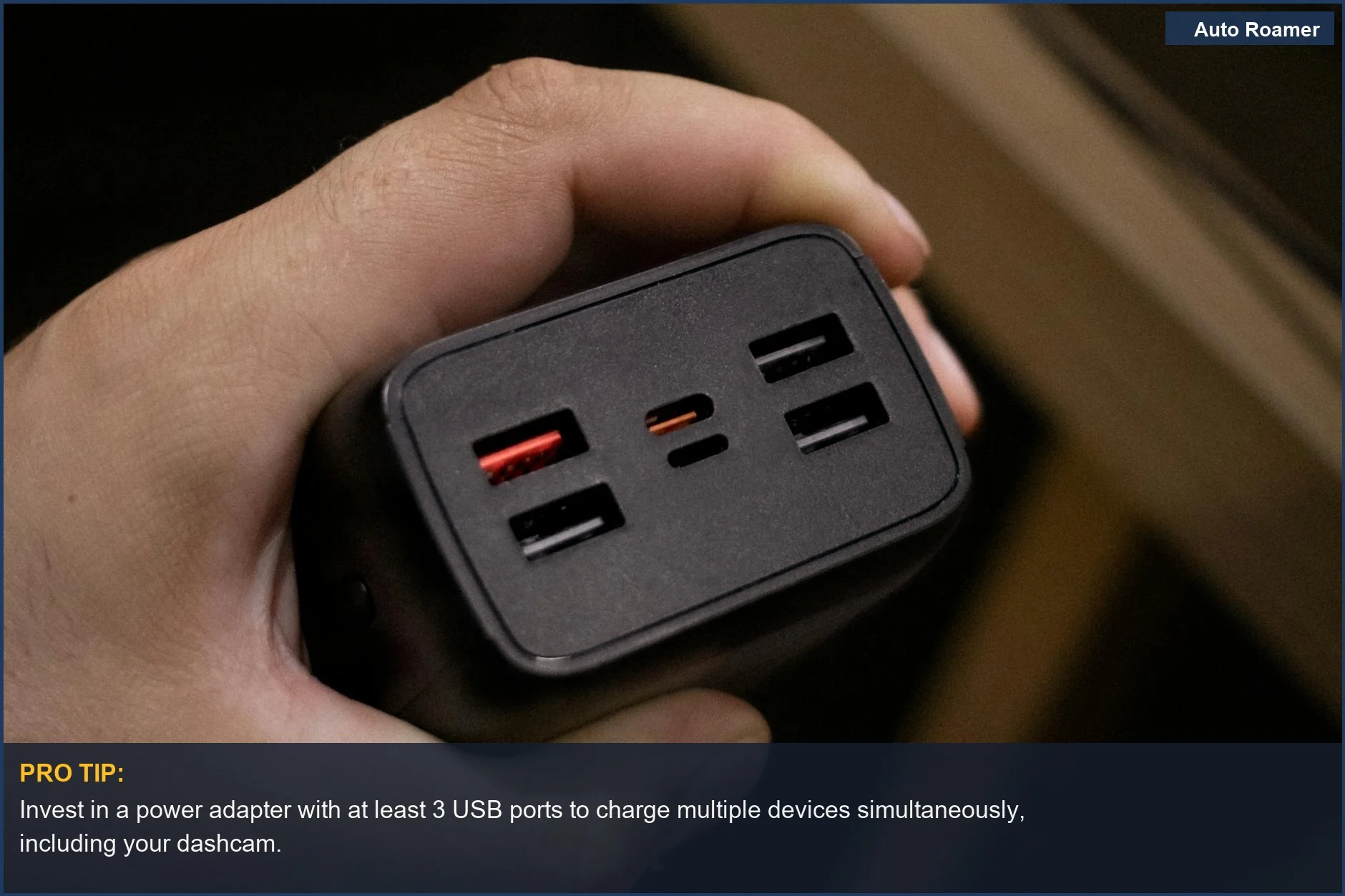 Hand holding a multi-USB port power adapter, ideal for charging dashcam batteries.