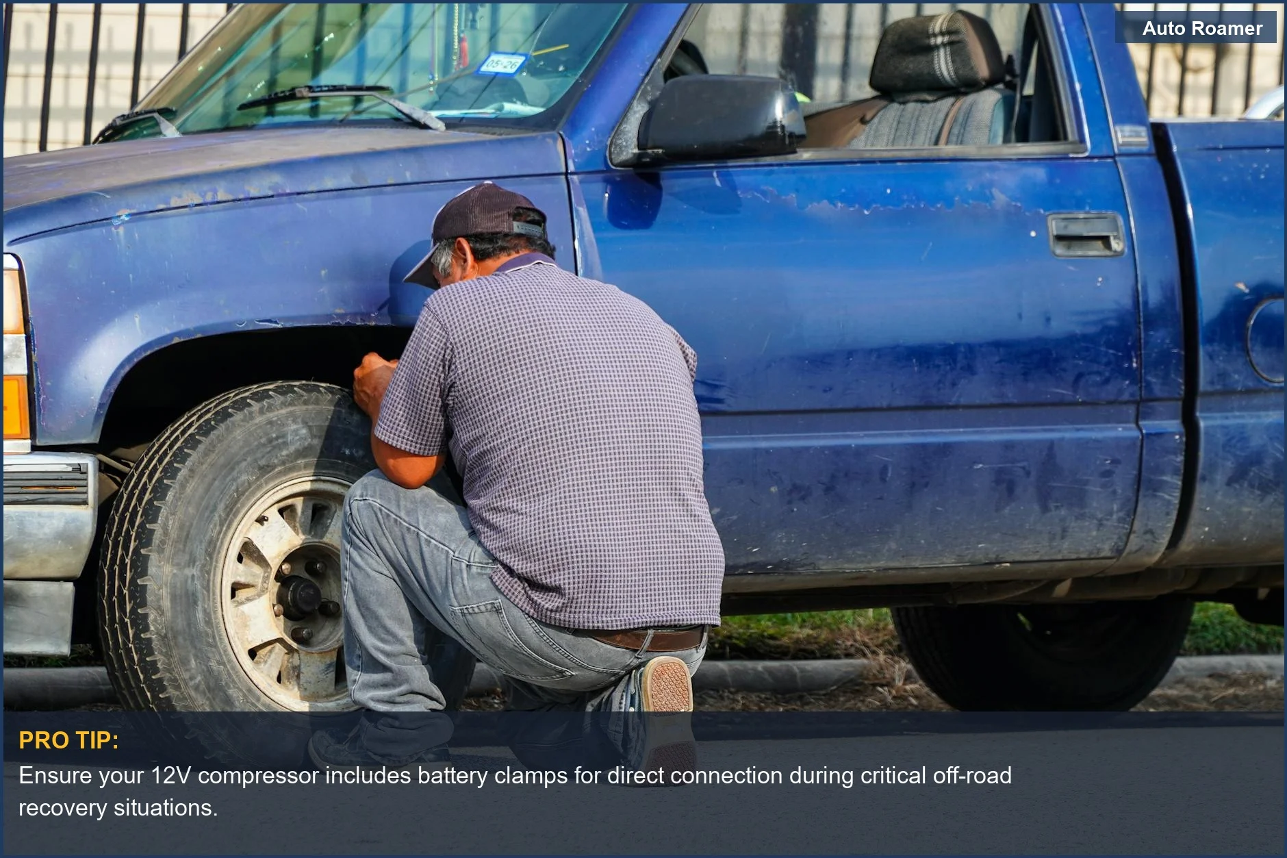 Man fixing a flat tire on a truck, showcasing off-road recovery with a 12V compressor.