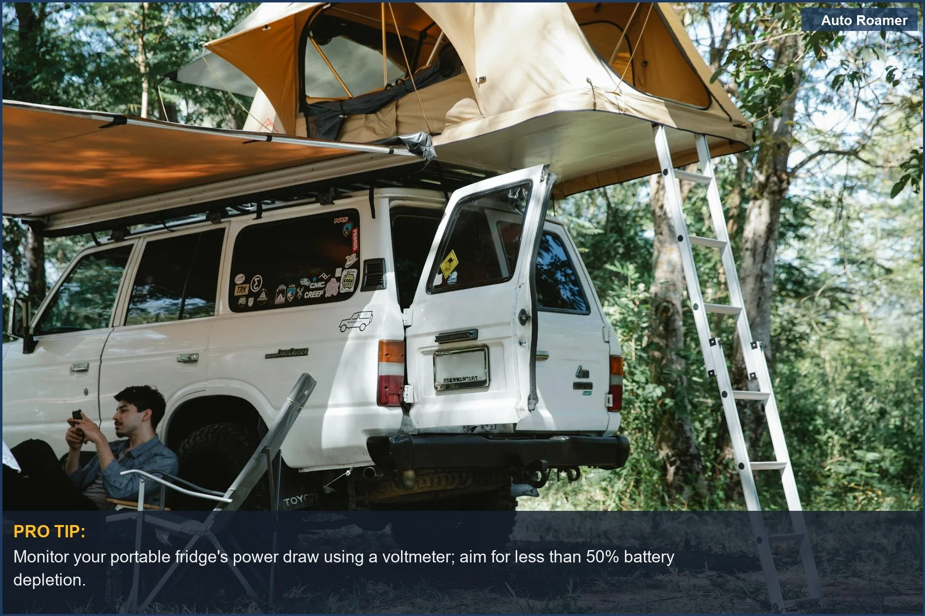 Man with smartphone near offroad vehicle and rooftop tent, highlighting car camping fridge power.