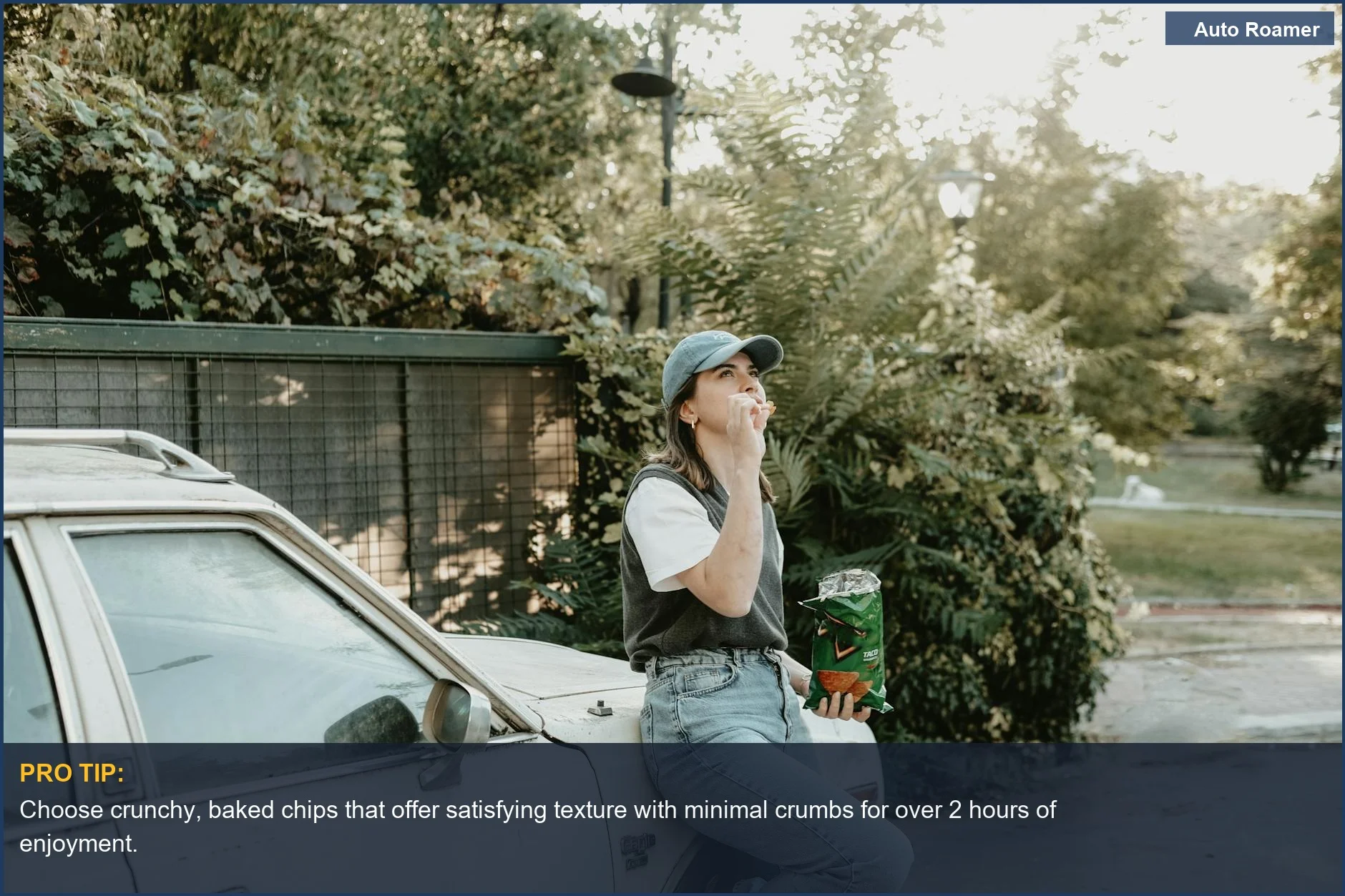 Woman happily eating chips while leaning on car during a sunny day road trip.