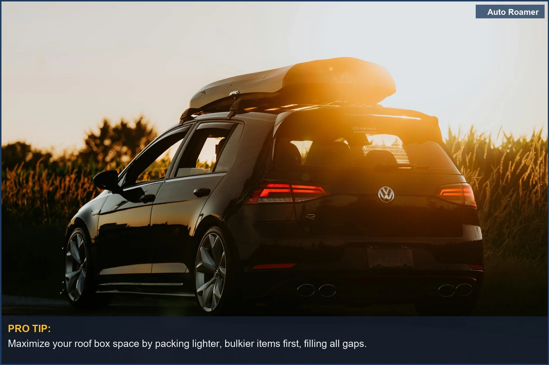 Sleek black car with a roof box parked on a rural road at sunset, showcasing road trip storage options.
