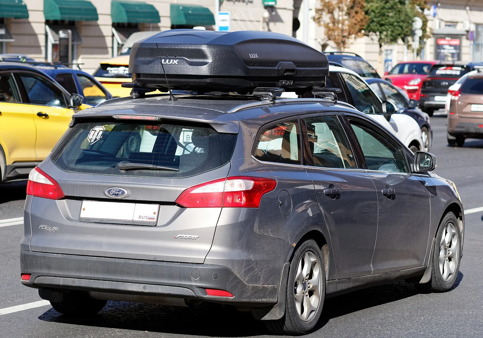 Car roof rack crossbars holding a hard-shell roof box on a Ford Focus