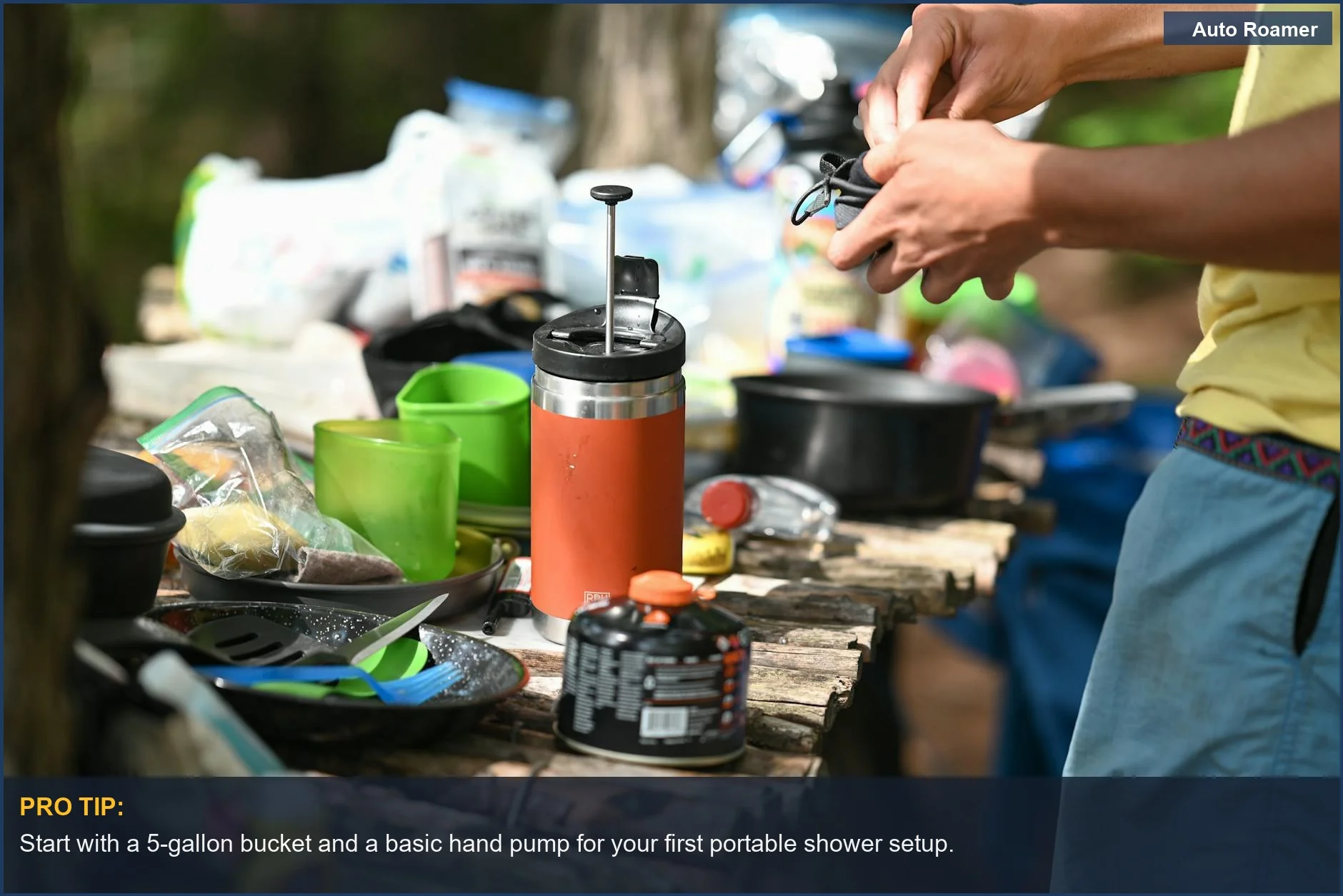 Setting up a portable shower setup with a water container and pump mechanism for car camping.