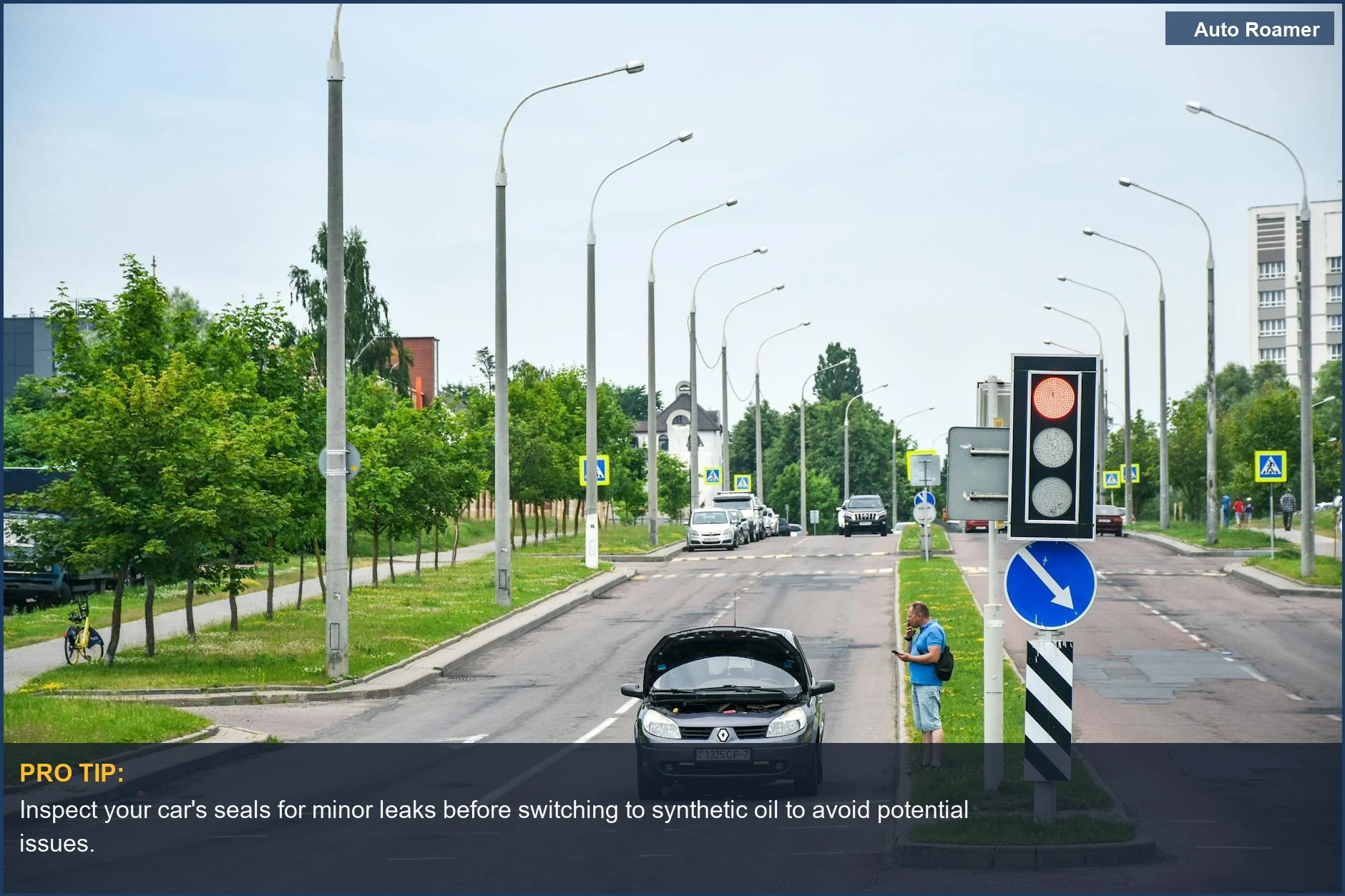 Man with broken car on street, checking phone, considering synthetic oil for older cars.