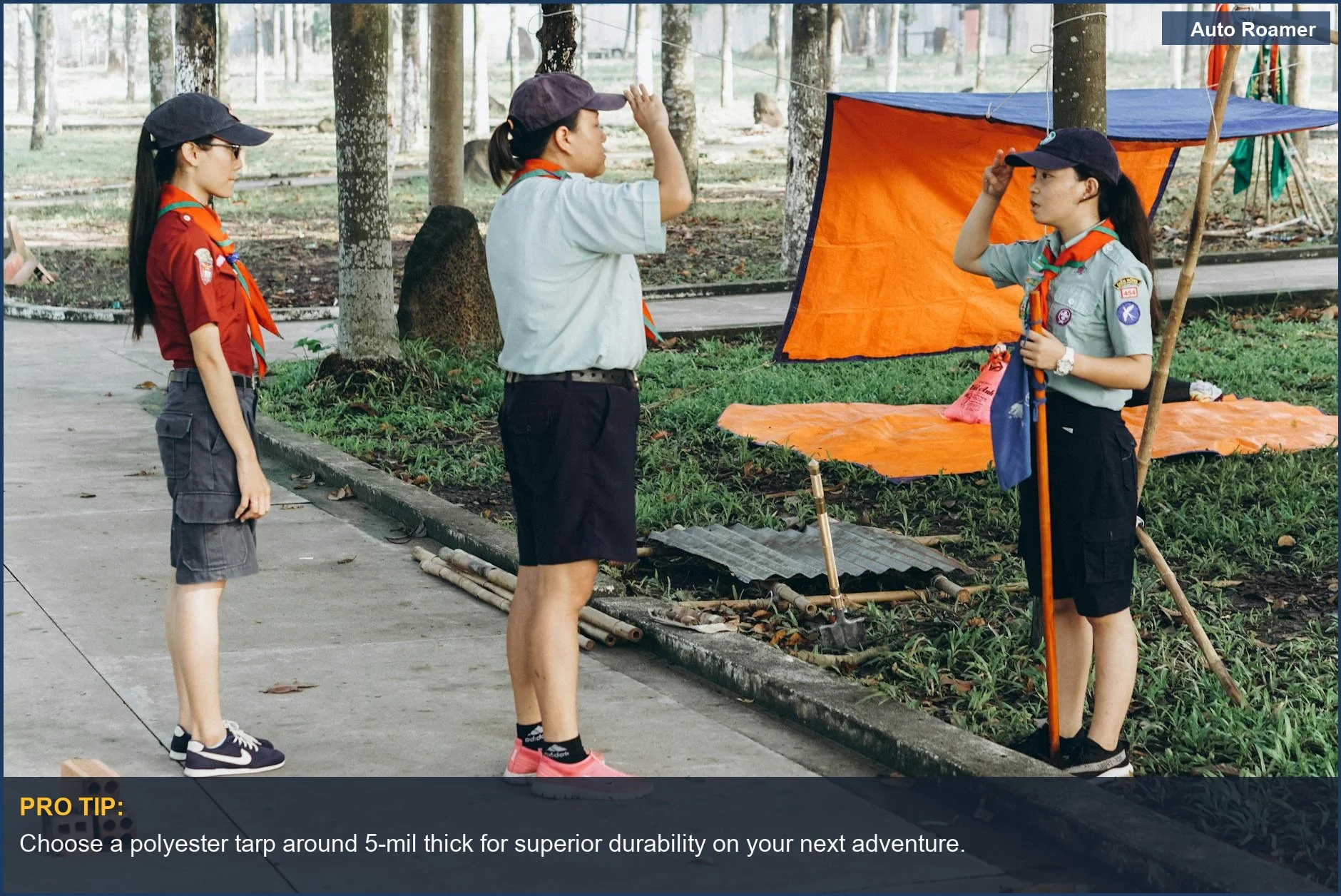 Scouts setting up an orange tarp for a car camping shelter in a park.