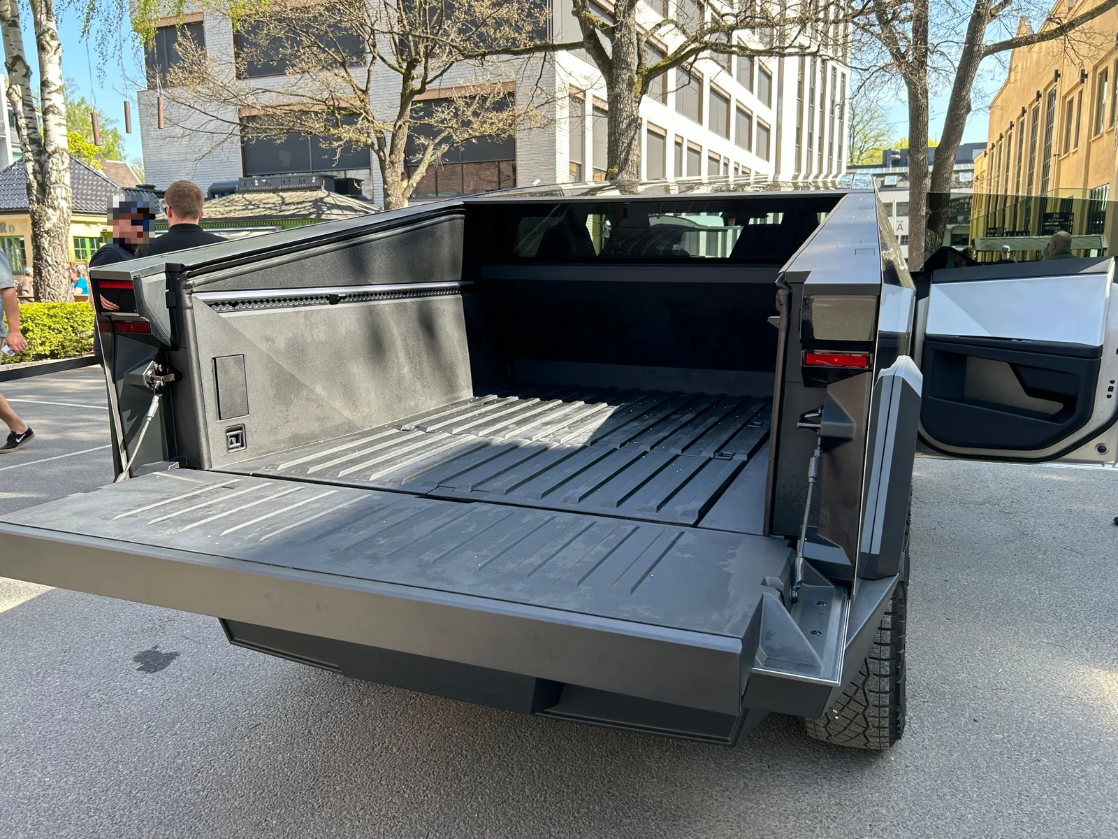 A stainless Tesla Cybertruck with its rear bed tonneau open, the Vault load bed this guide treats as the sleeping platform.