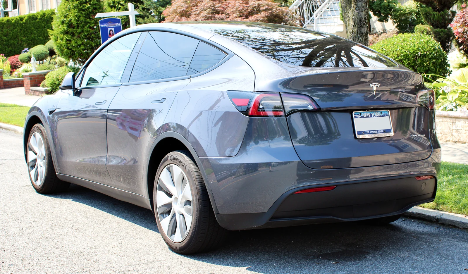 A white Tesla Model Y seen from the rear three-quarter, the liftgate and flat load floor that matter when fitting a camping mattress.