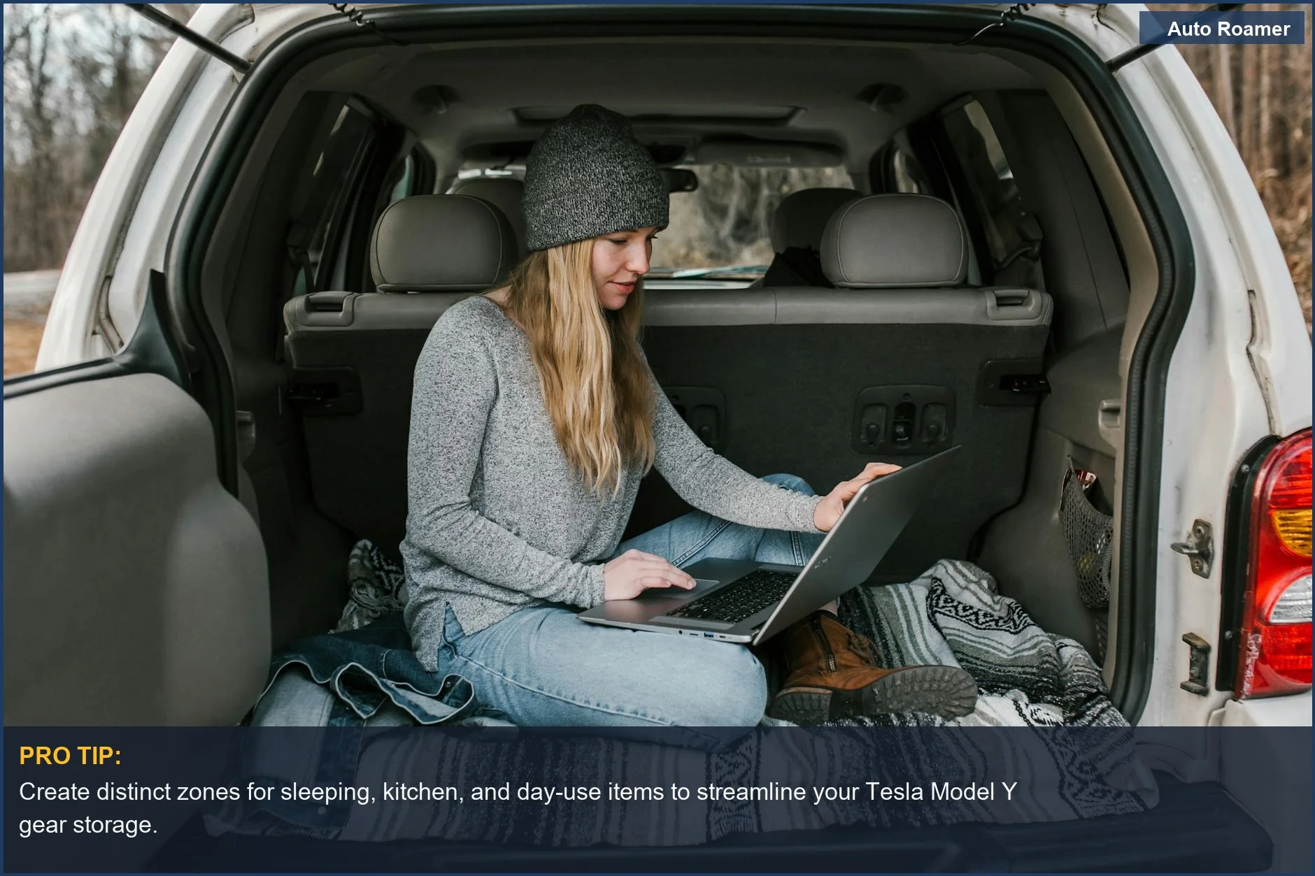 Woman working on laptop in organized Tesla Model Y trunk, showcasing efficient car camping organization.