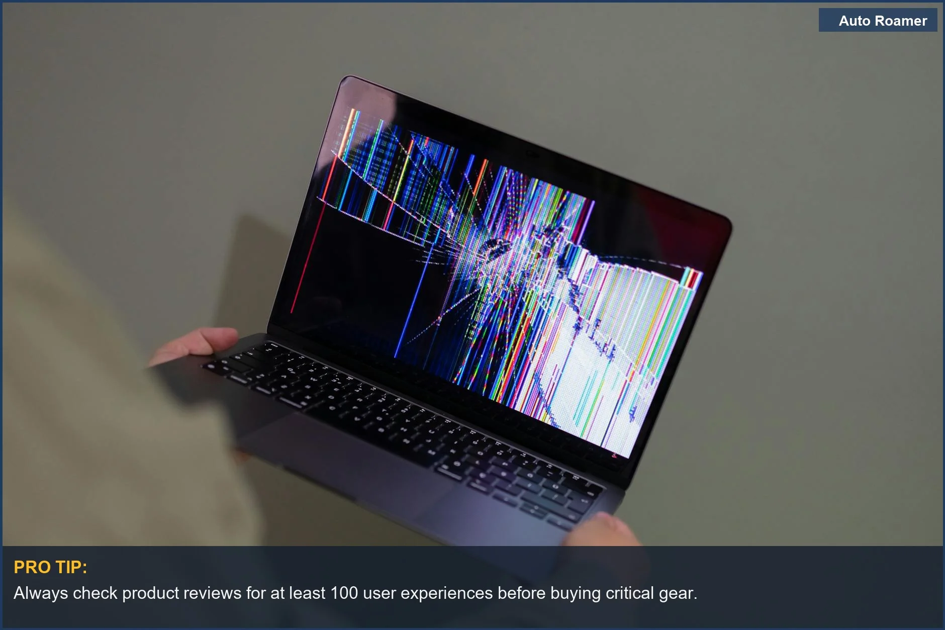 Person holding a broken laptop with glitching screen, emphasizing the true cost of cheap road trip gear failure.
