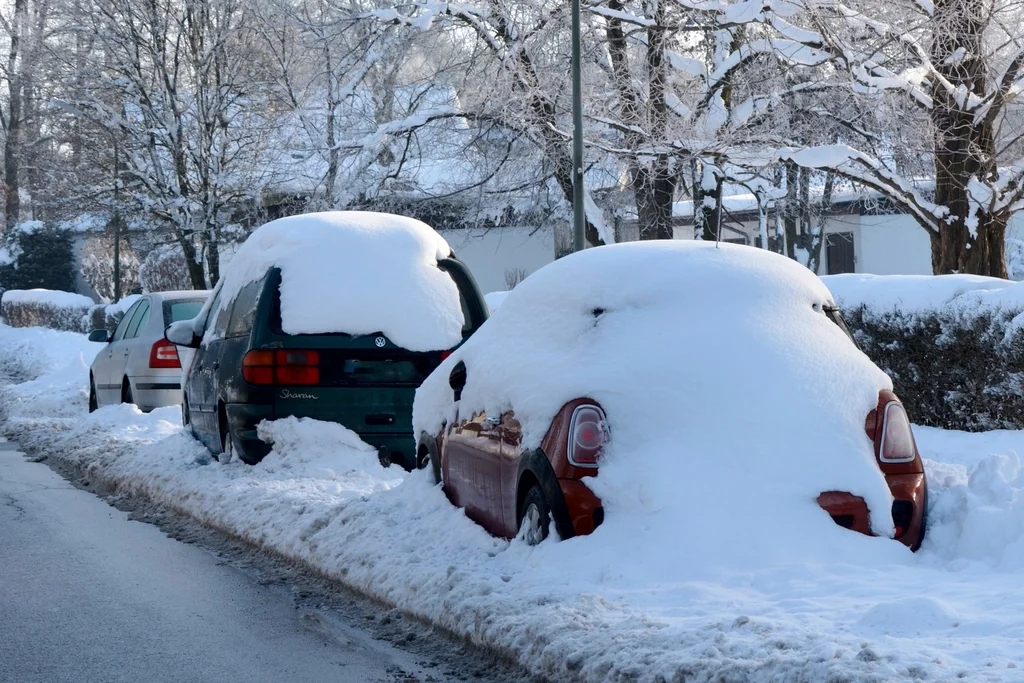 A car covered in fresh snow on a frigid night, the kind of cold this guide warns can make sleeping in a vehicle unsafe.