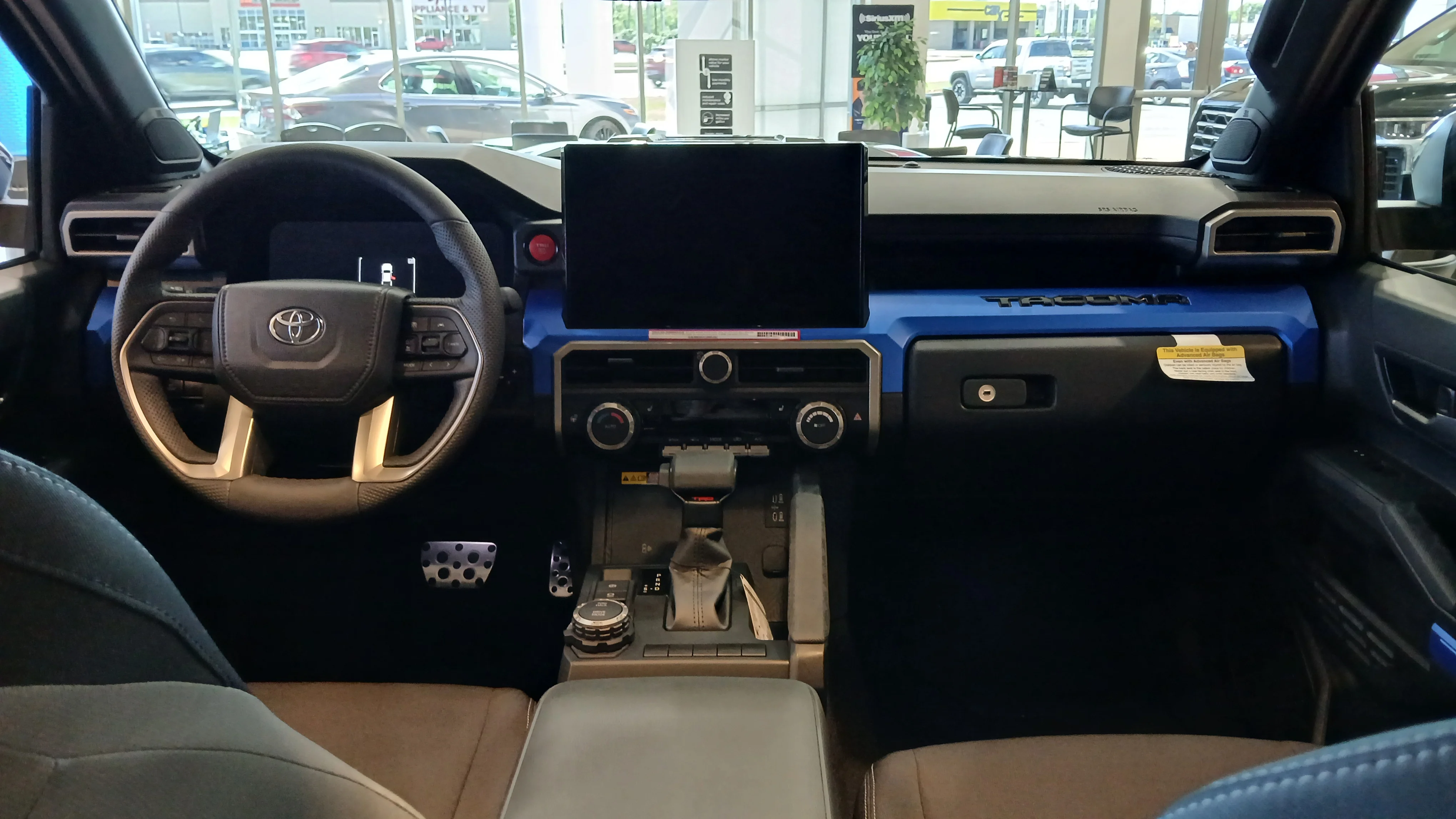 The interior and dashboard of a 2024 Toyota Tacoma TRD, the cabin beside the i-FORCE MAX hybrid power system this guide runs camp gear from.