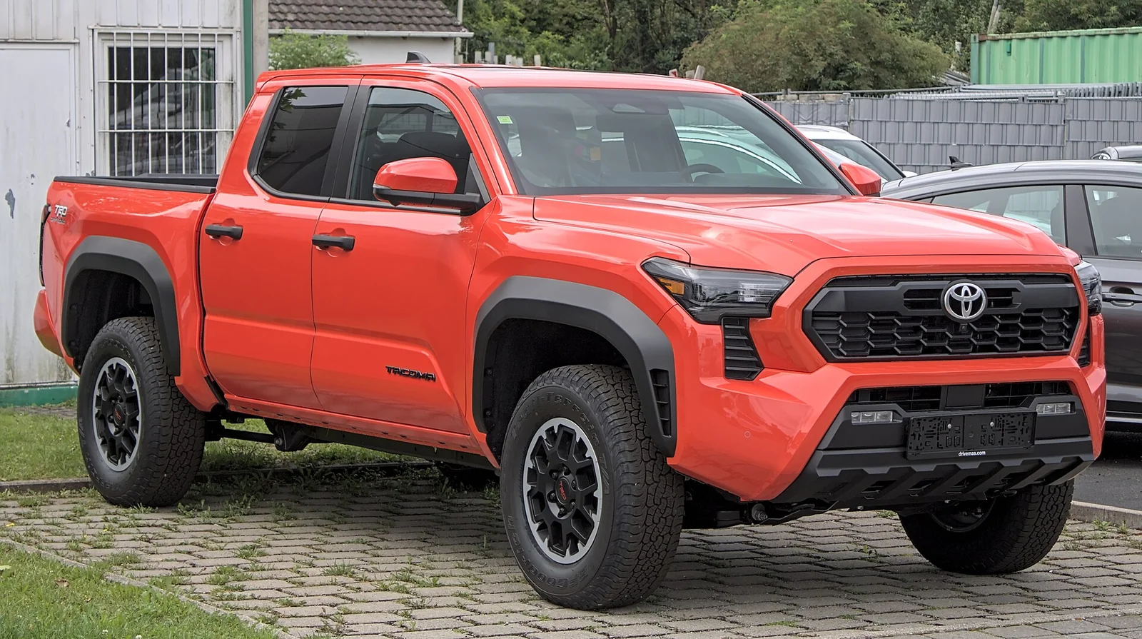 An orange current-generation Toyota Tacoma TRD, the midsize truck this comparison builds a camping bed and galley around.