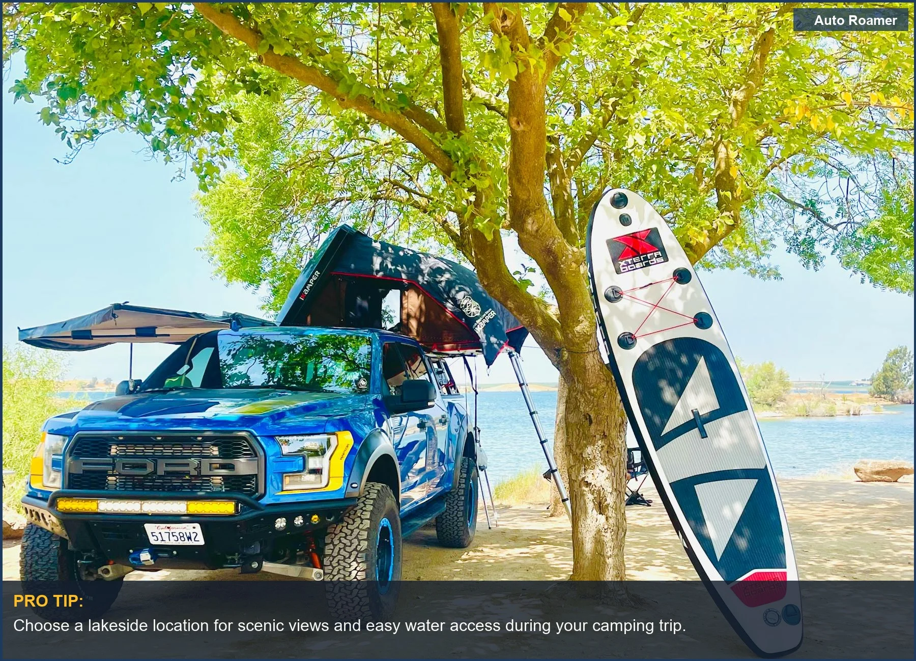 Off-road truck with camping gear and paddleboard by scenic lake -- truck camping essentials