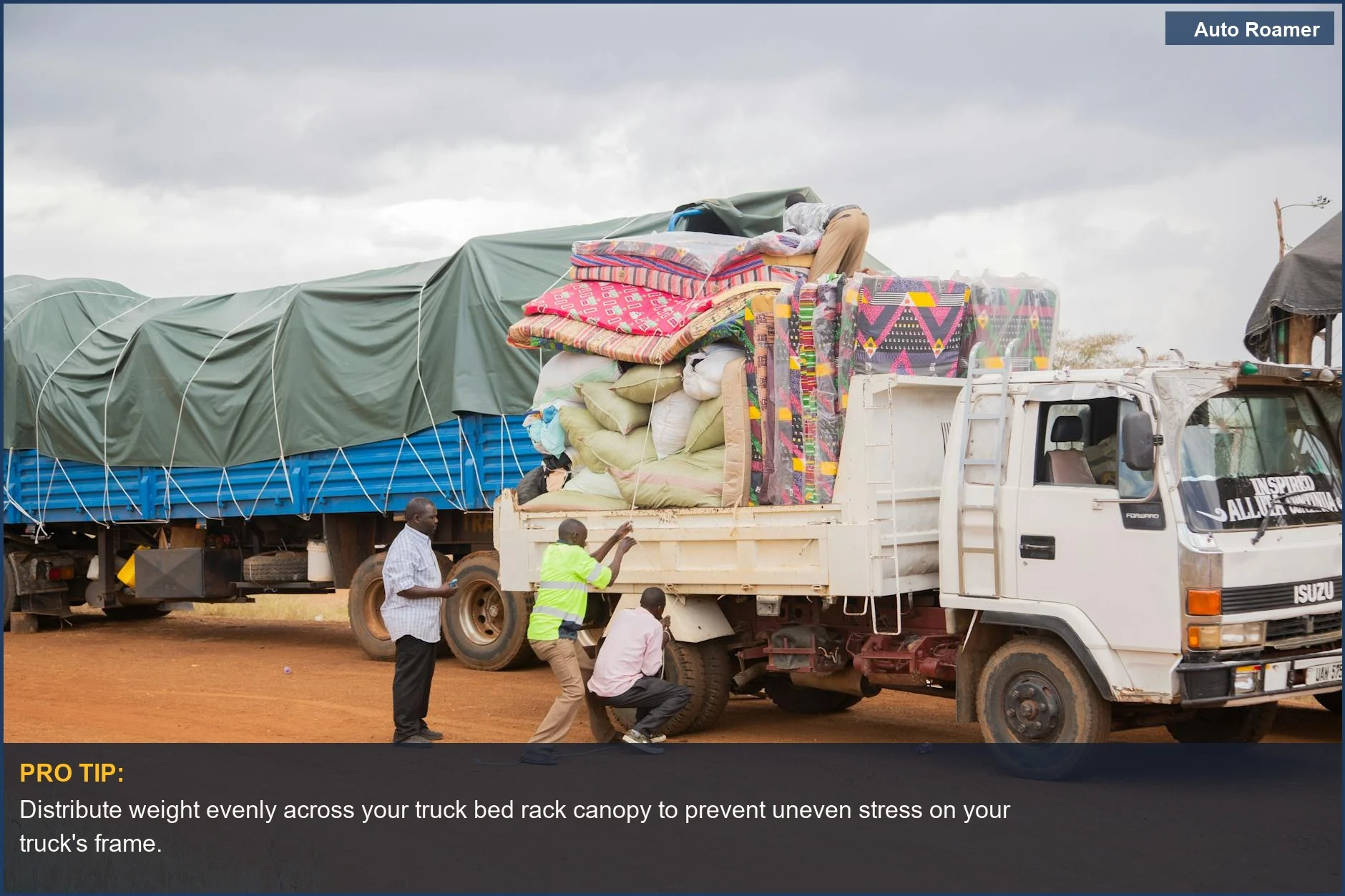 Loading supplies onto a truck bed rack canopy in a rural setting under cloudy skies.