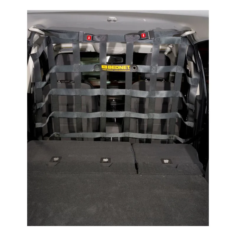 A gray webbing barrier cargo net installed vertically behind the rear seats of an SUV, separating the cargo area from the cabin