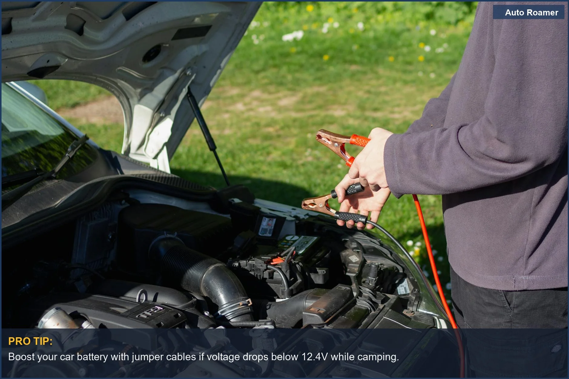 Man using jumper cables on a car engine, a common solution for car battery drain while camping.