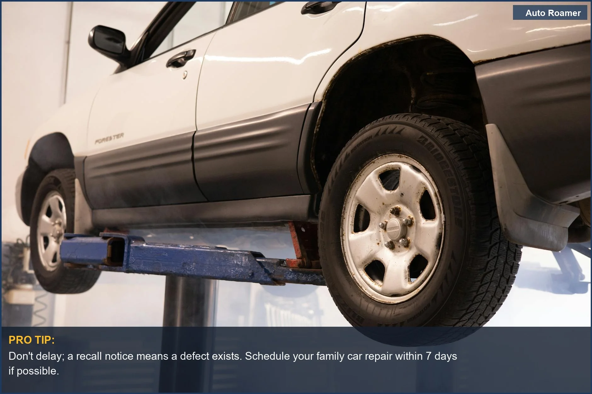 White car suspended on a lift in a repair shop, illustrating the need for prompt action on vehicle recall notices.