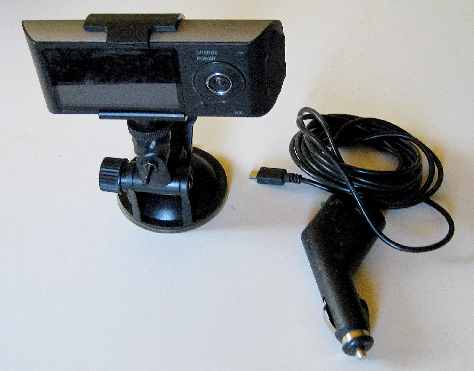 Dash cam with its suction-cup windshield mount alongside a long 12-volt power cord and cigarette-lighter adapter