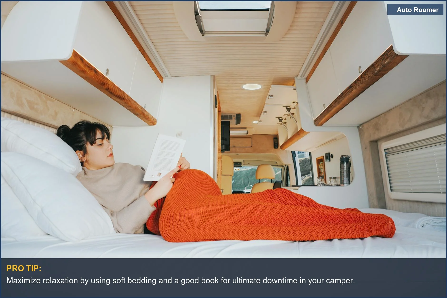 Woman reading comfortably in a cozy 2026 Volkswagen California camper van bed with a blanket.